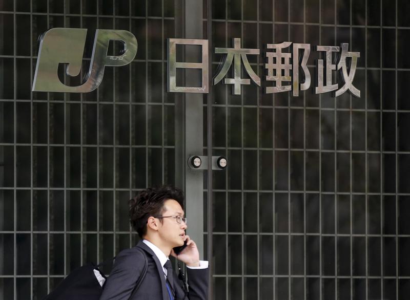 A man walks past a logo of Japan Post Group at its headquarters in Tokyo    