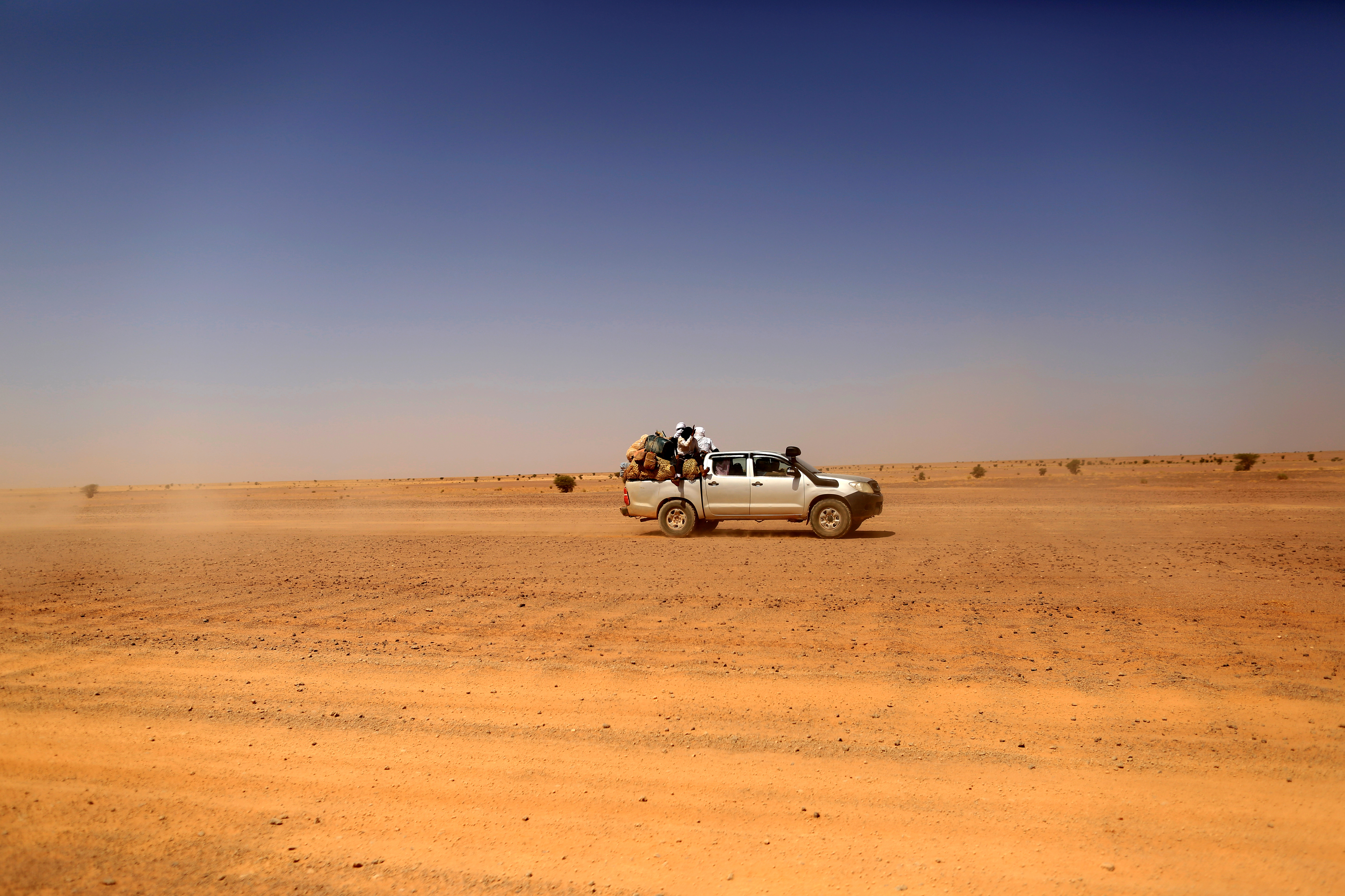 Indigenous Sahrawi people sit on a pick-up truck as they drive towards Tifariti, Western Sahara,