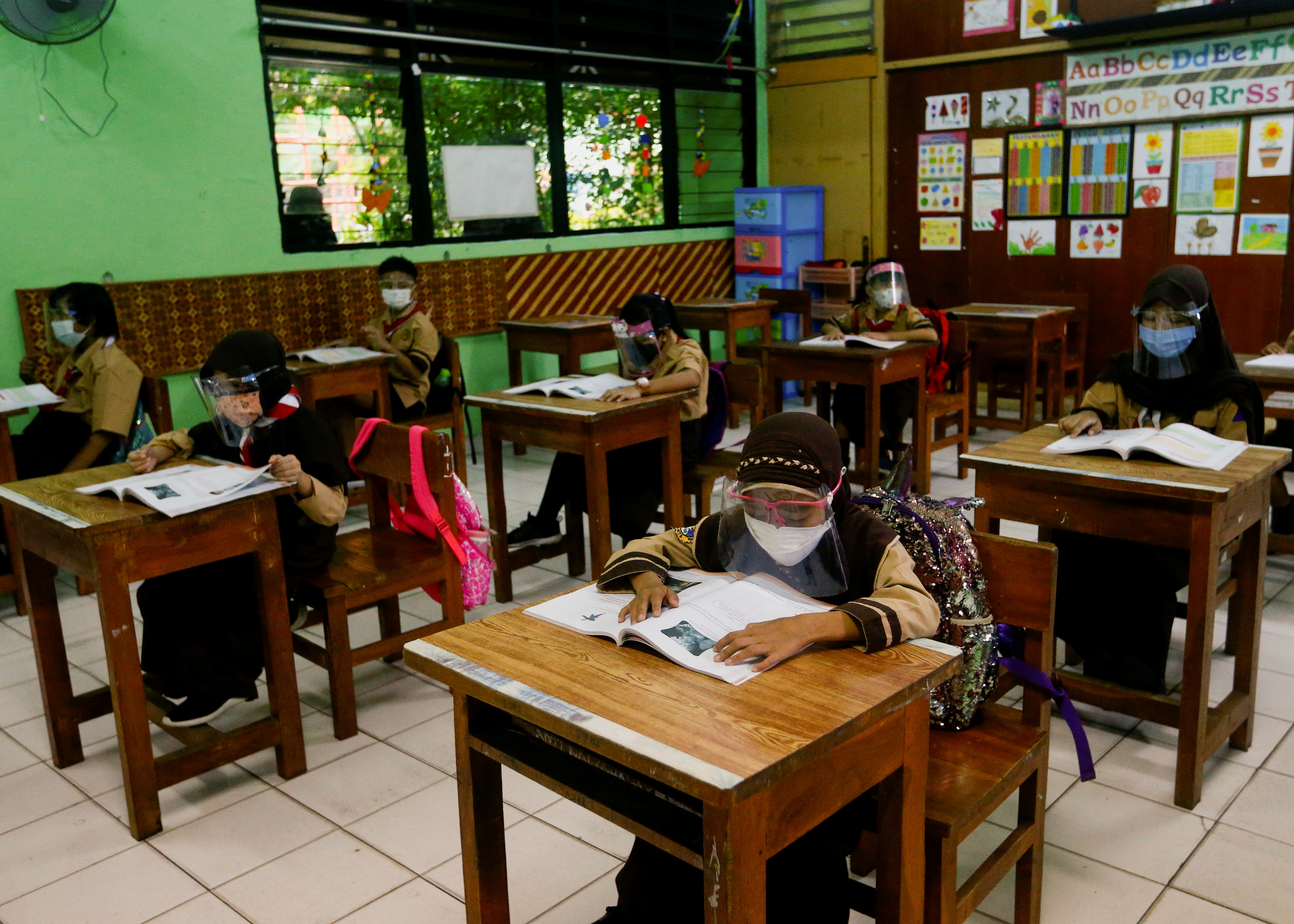 Elementary school students wearing face masks and face shields attend class, as schools reopen amid the coronavirus disease (COVID-19) pandemic, in Jakarta