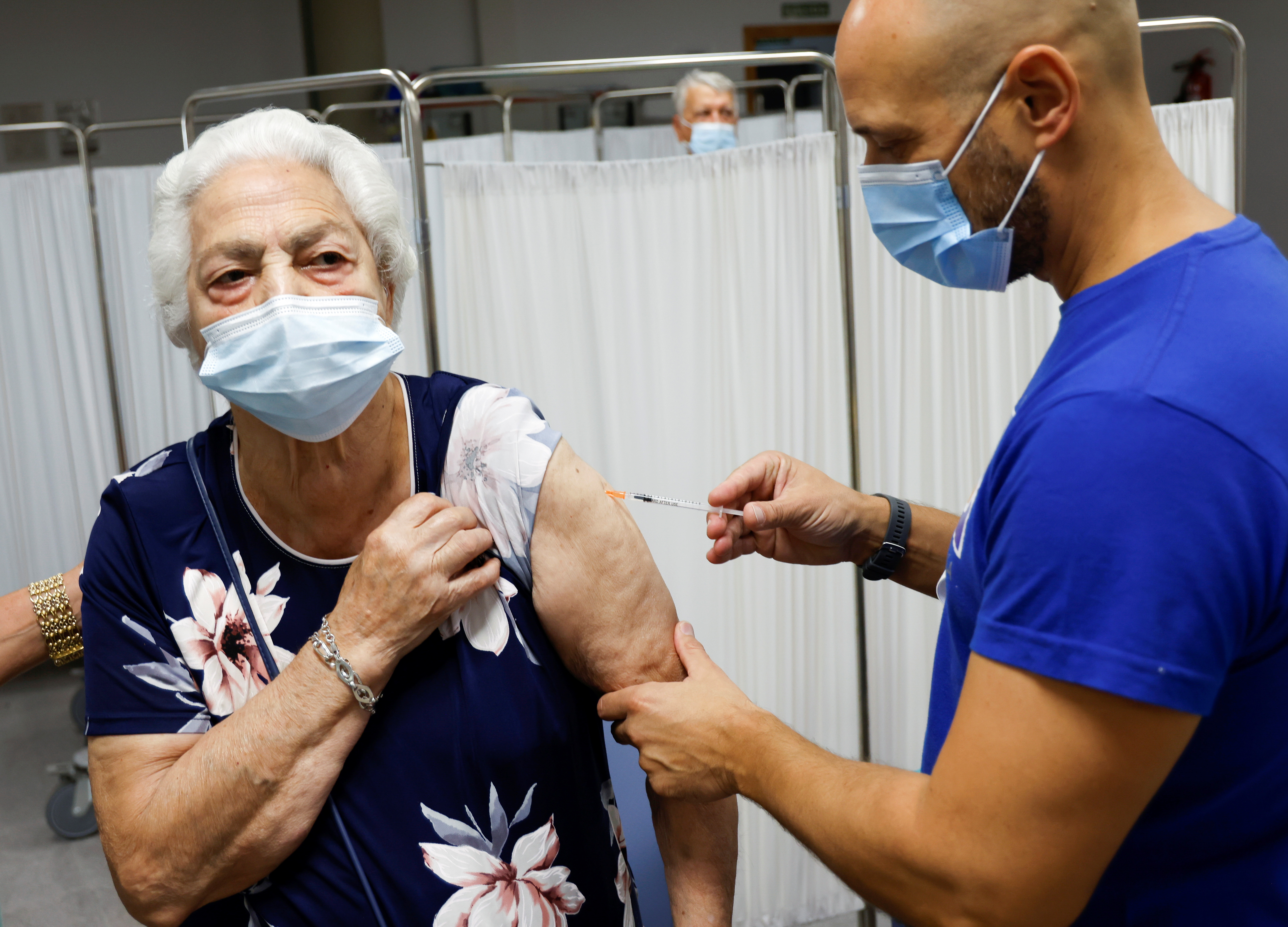 An elderly woman receives a coronavirus disease (COVID-19) vaccine booster coinciding with the flu vaccination campaign in Seville, Spain October 18, 2021. REUTERS/Marcelo del Pozo