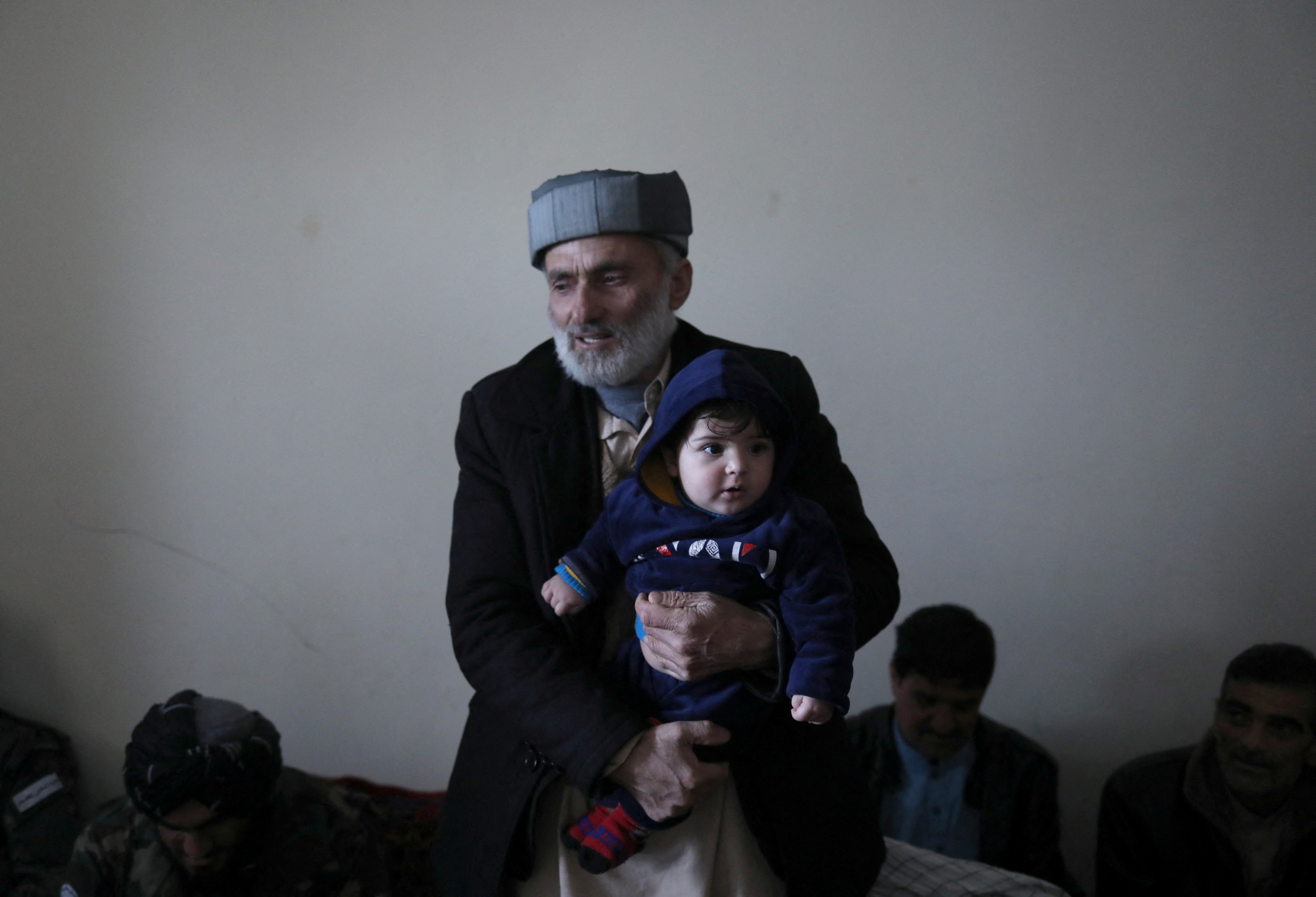 Mohammad Qasem Razawi, grandfather of baby Sohail Ahmadi, holds him at the house of Hamid Safi in Kabul