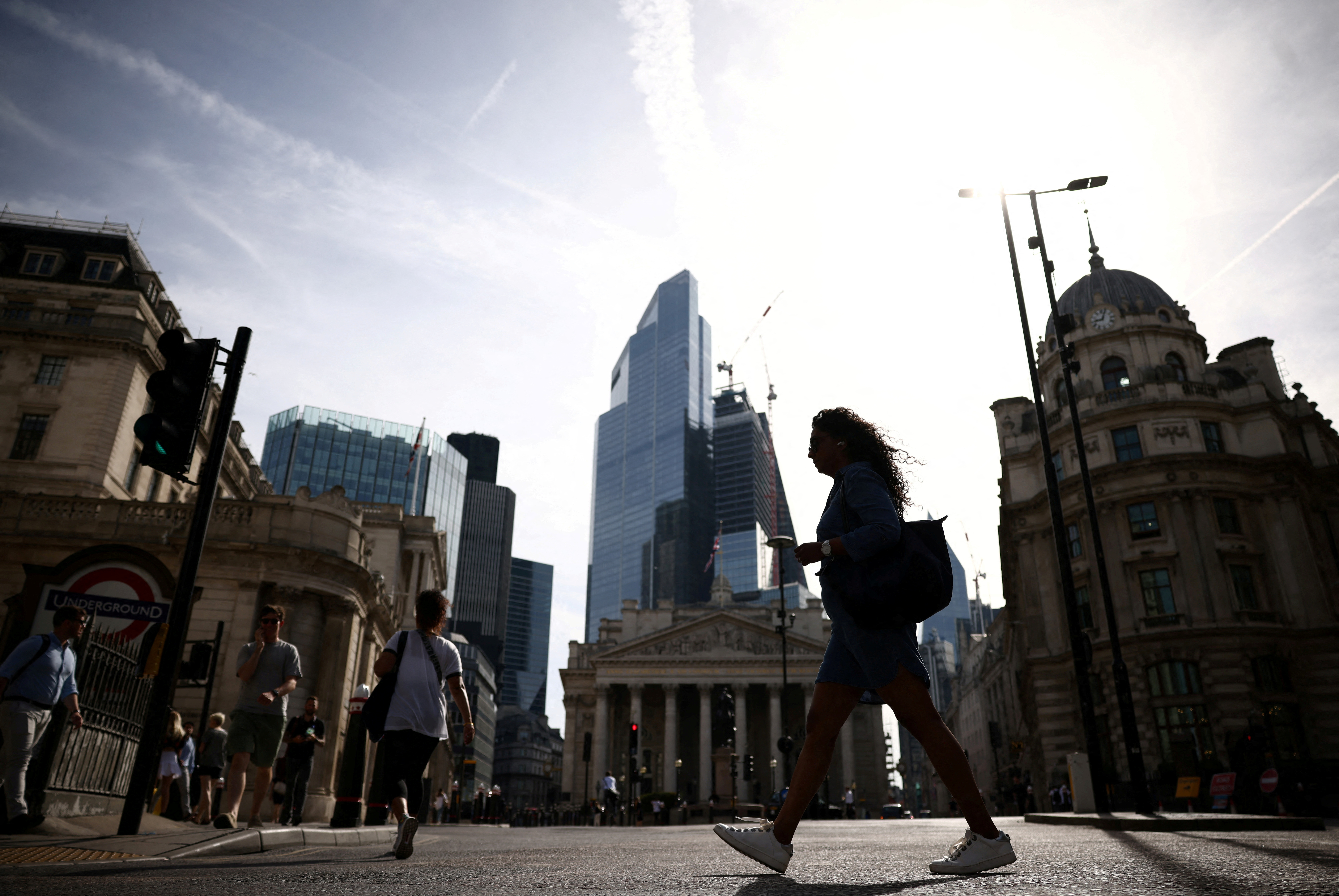 People walk through the City of London financial district during warm weather in London