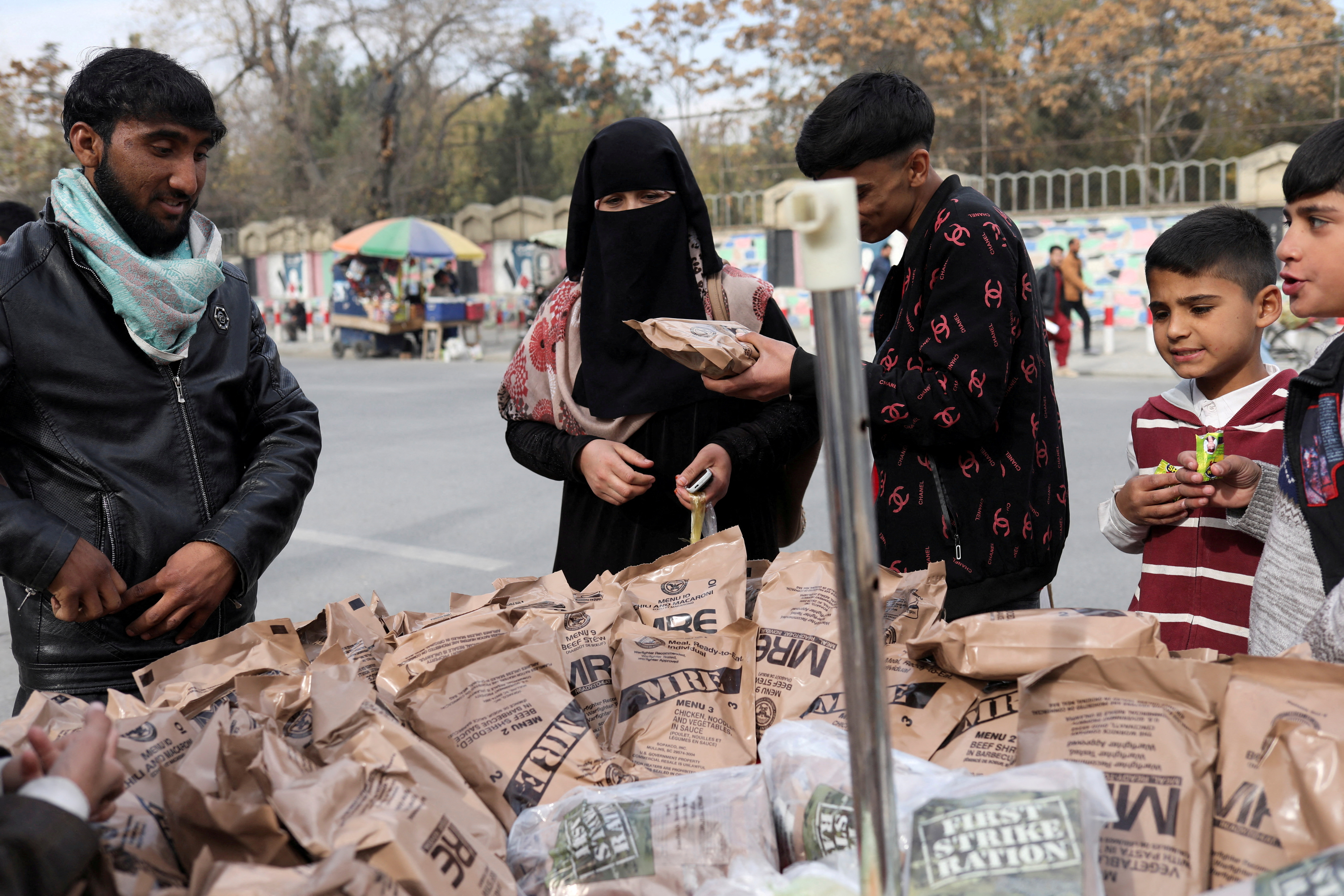 Afghan woman buys food left behind by the US military from a peddler in Kabul