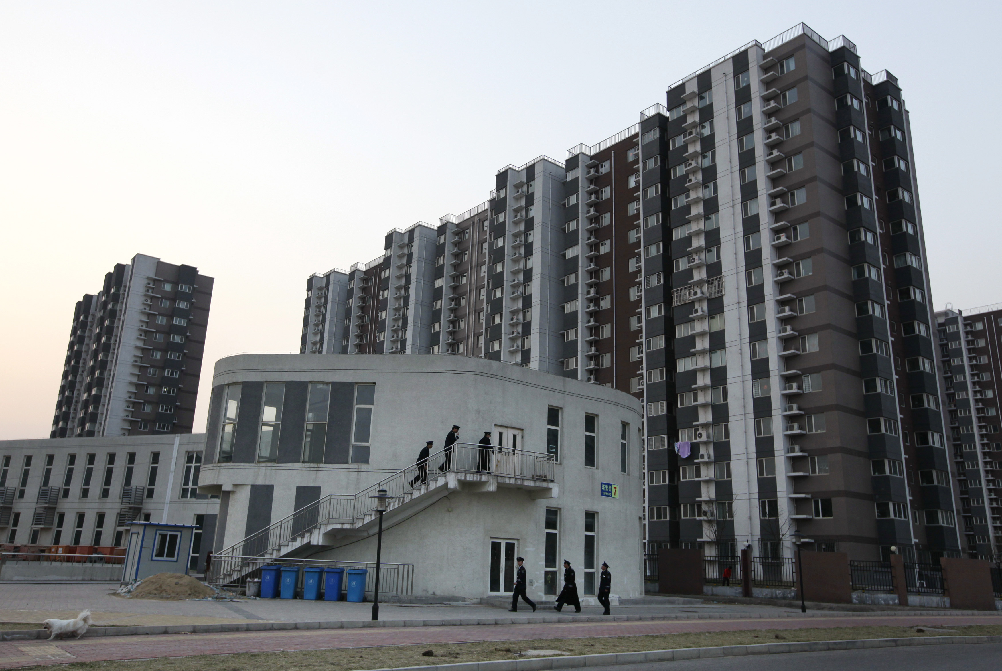 Security guards walk into a building in front of apartment blocks in Beijing