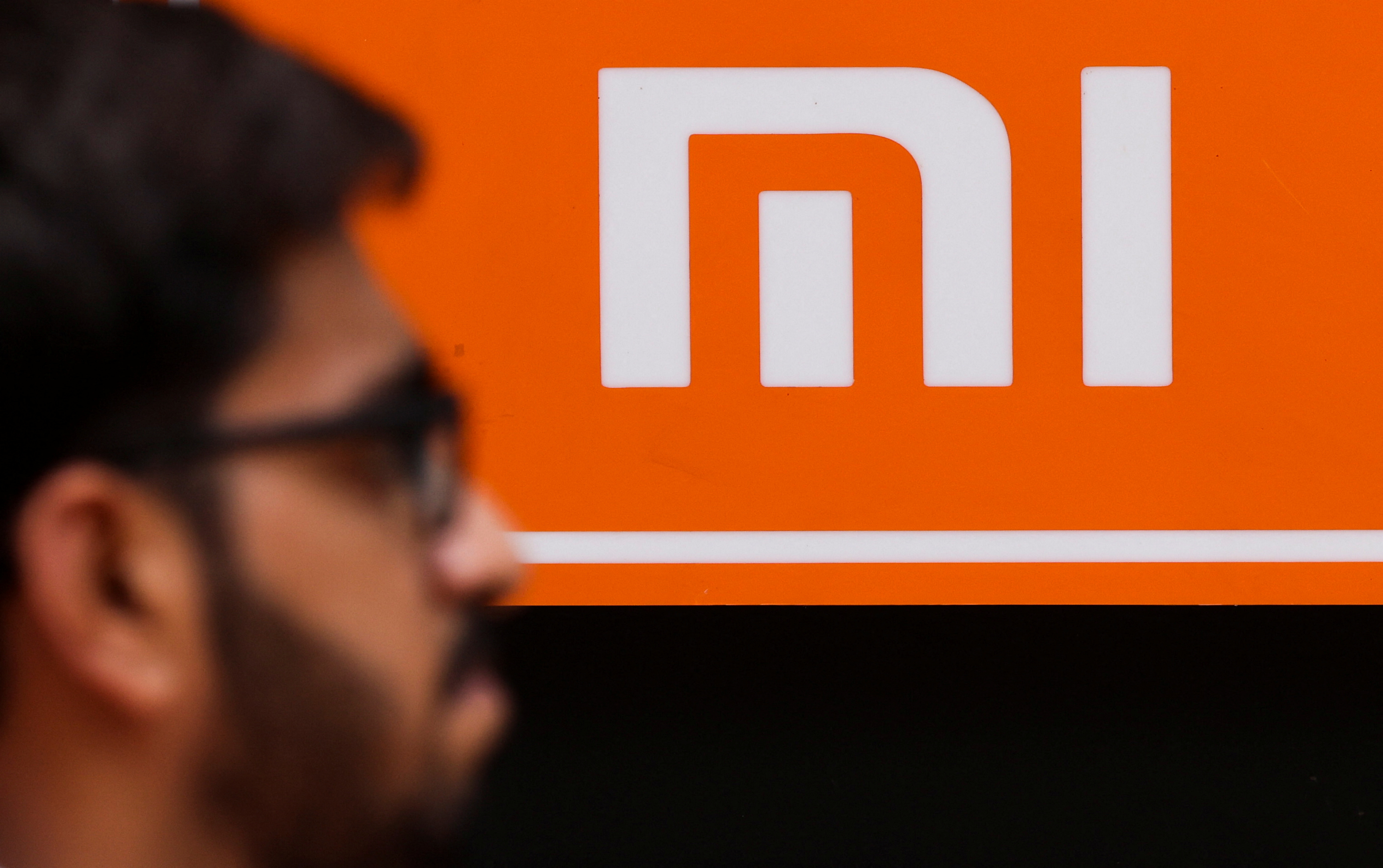 A man walks past a logo of Xiaomi, a Chinese manufacturer of consumer electronics, outside a shop in Mumbai