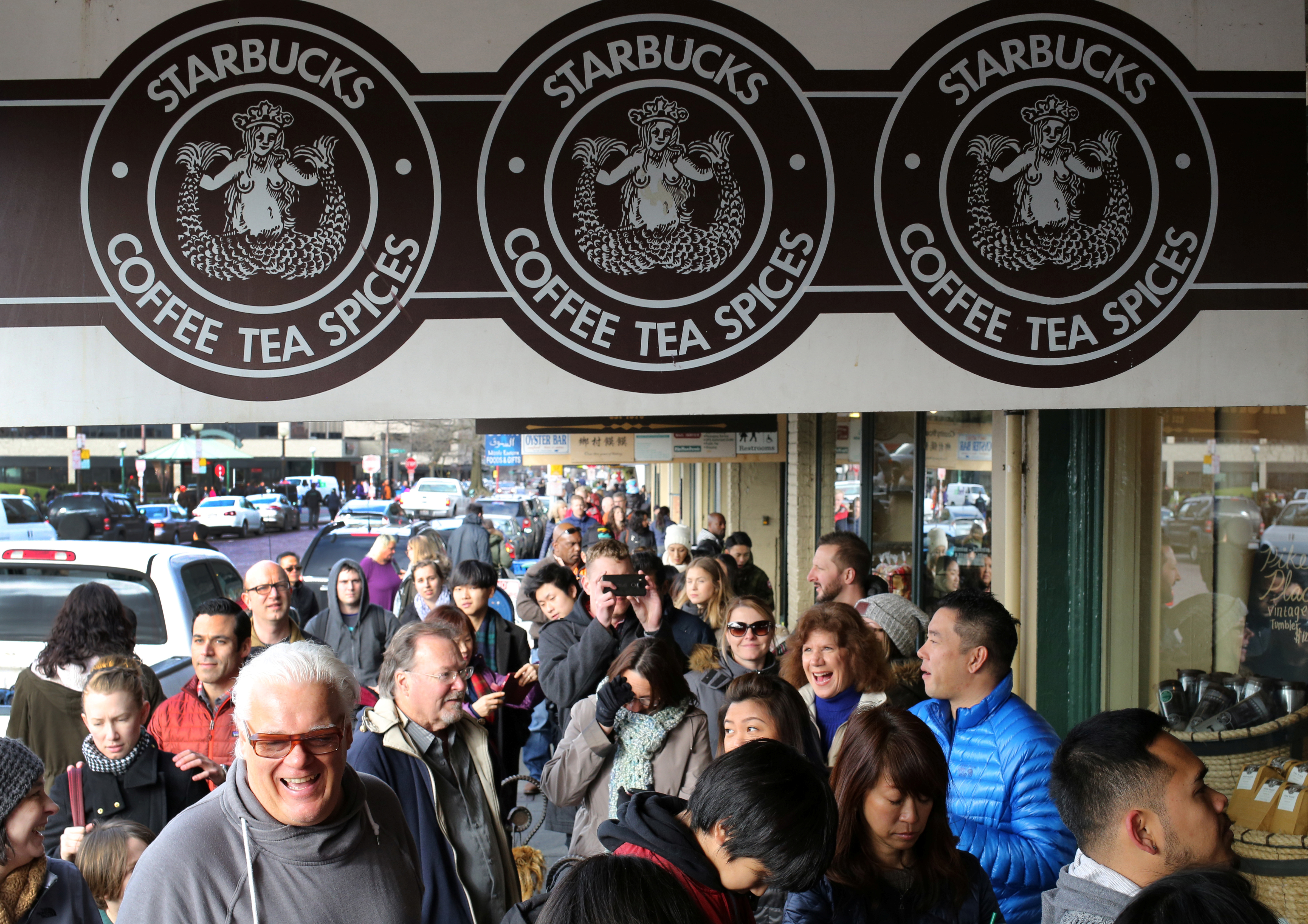 People form a line to enter the original Starbucks coffee shop at Pike Place Market in Seattle