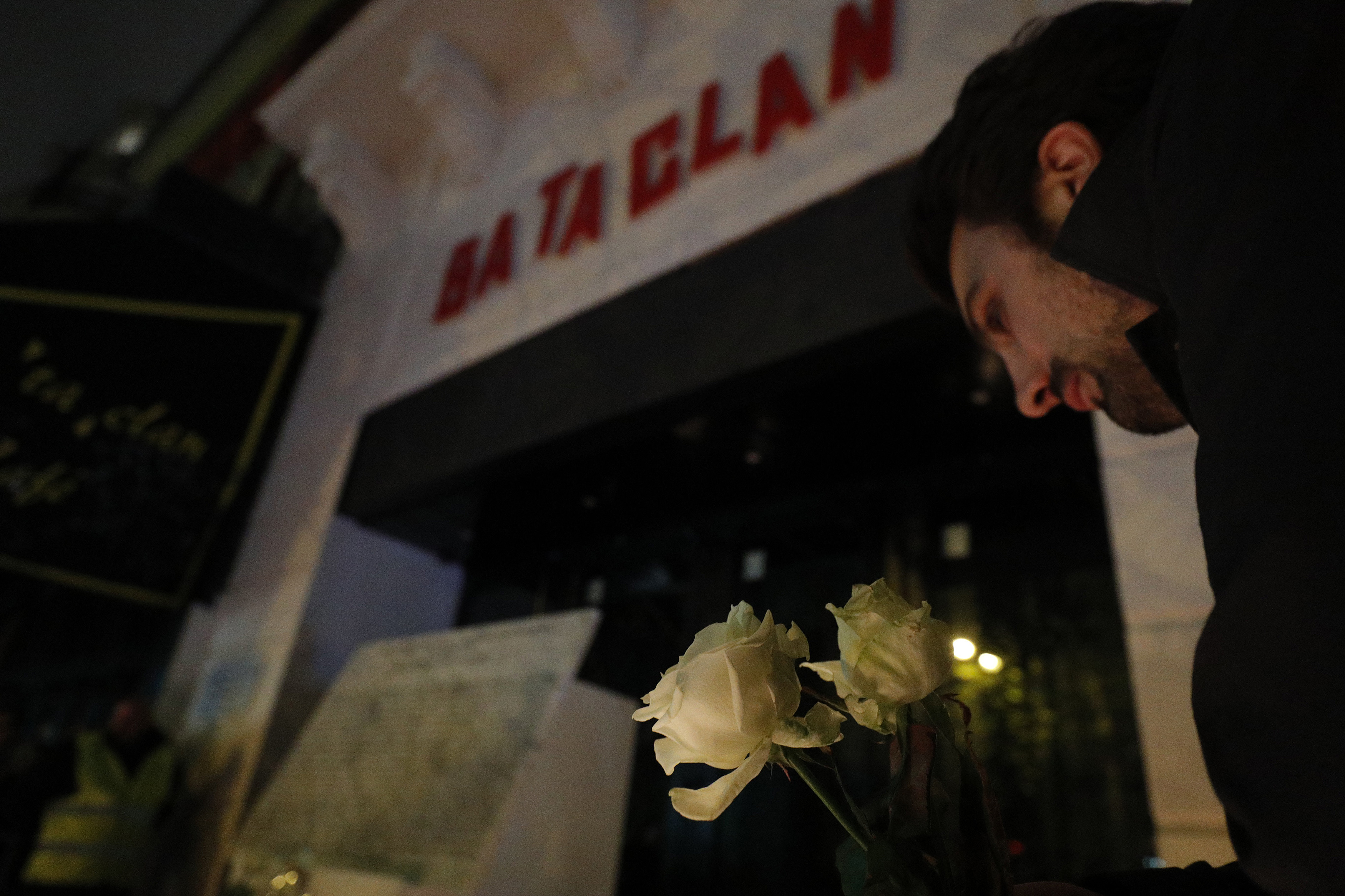 A man lays a white rose next to a commemorative plaque unveiled by French President Francois Hollande and Paris Mayor Anne Hidalgo during a gathering in front of the Bataclan concert hall in Paris