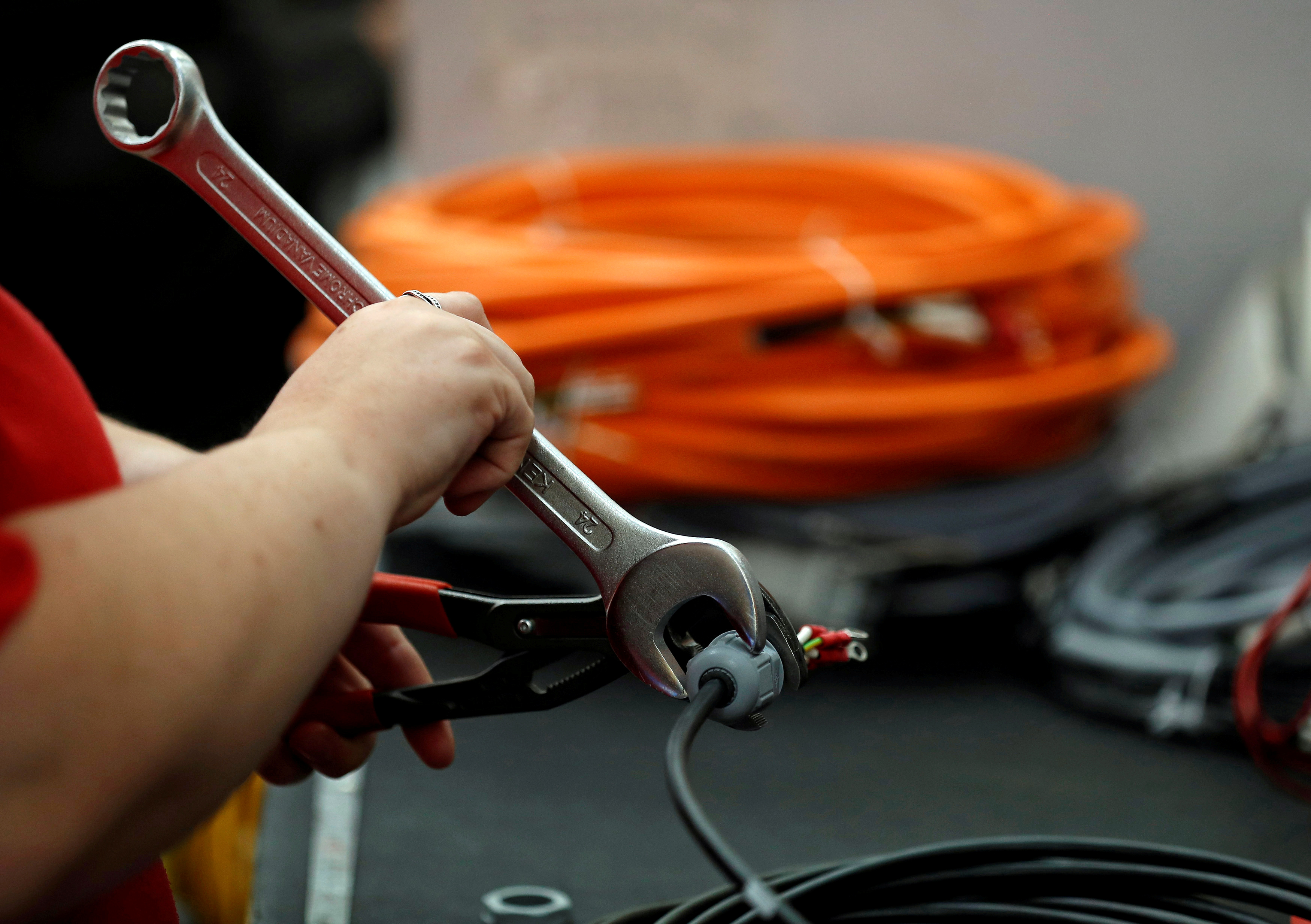 A worker attaches a connector to electrical wire on the factory floor of PP Control and Automation near Cannock, Britain, July 6, 2016. REUTERS/Phil Noble/File Photo