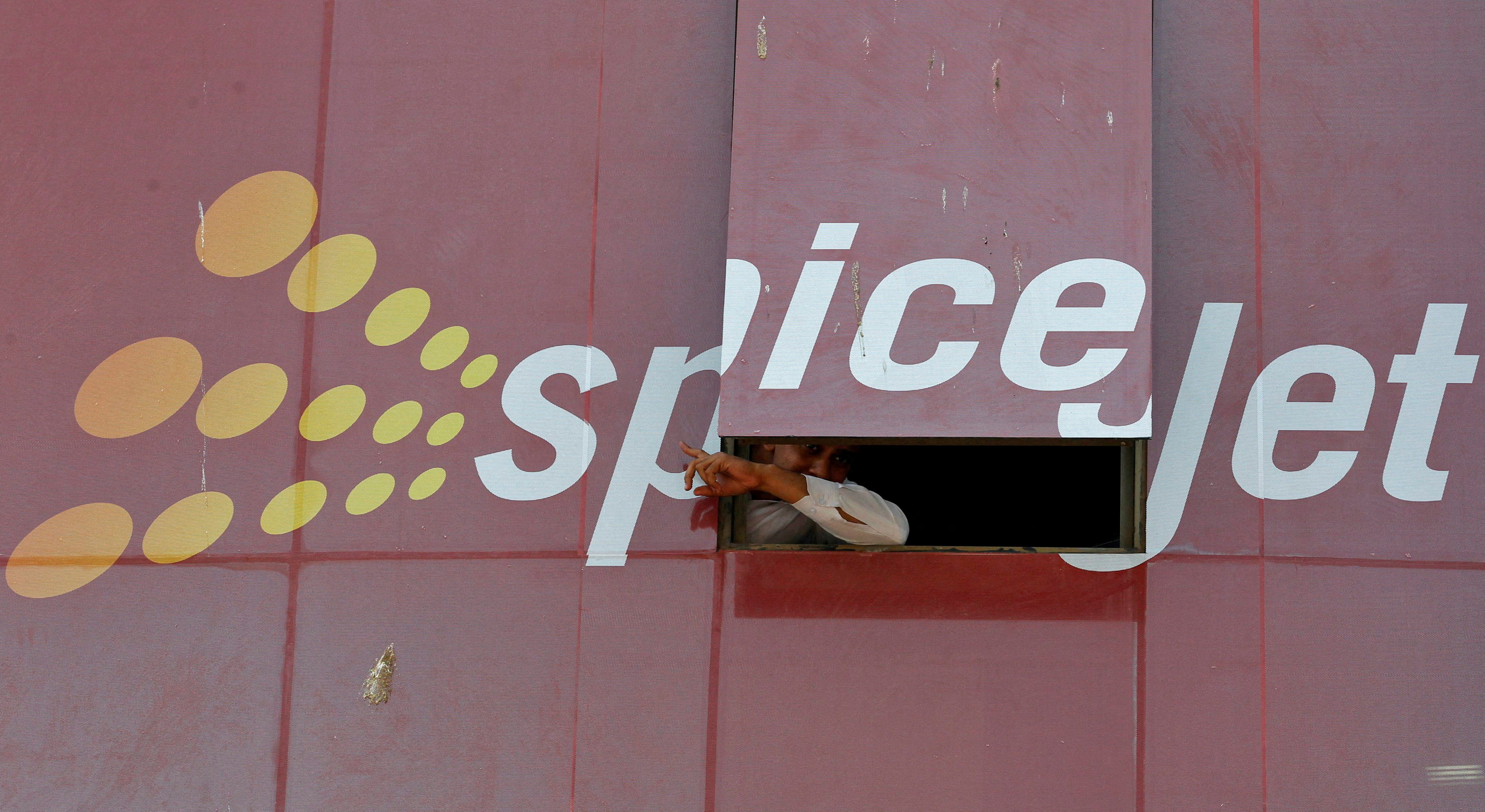 Man looks out through a window with an advertisement of SpiceJet Airline, on a commercial building in the western Indian city of Ahmedabad