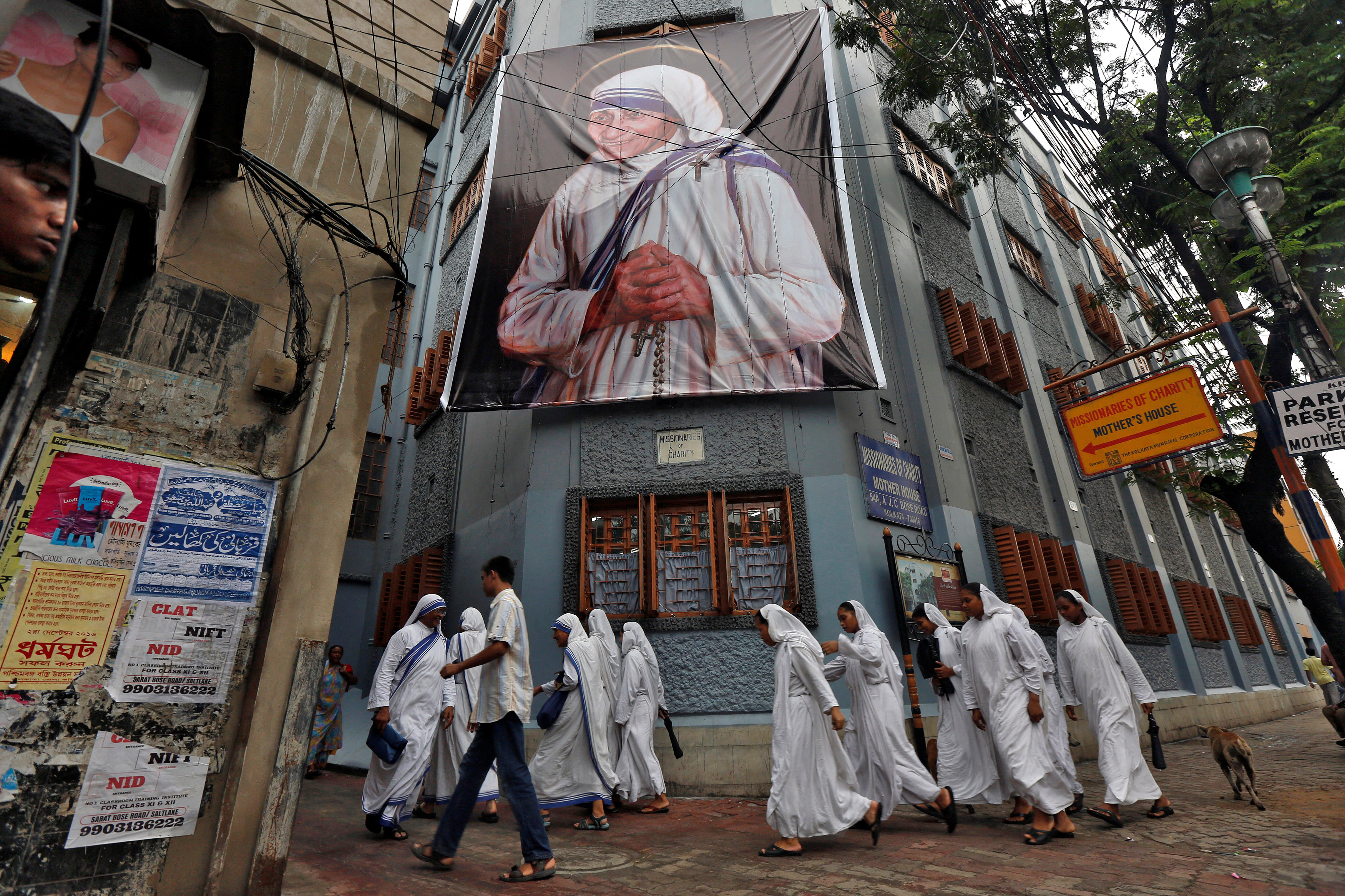 Nuns belonging to the global Missionaries of Charity, walk past a large banner of Mother Teresa ahead of her canonisation ceremony, in Kolkata