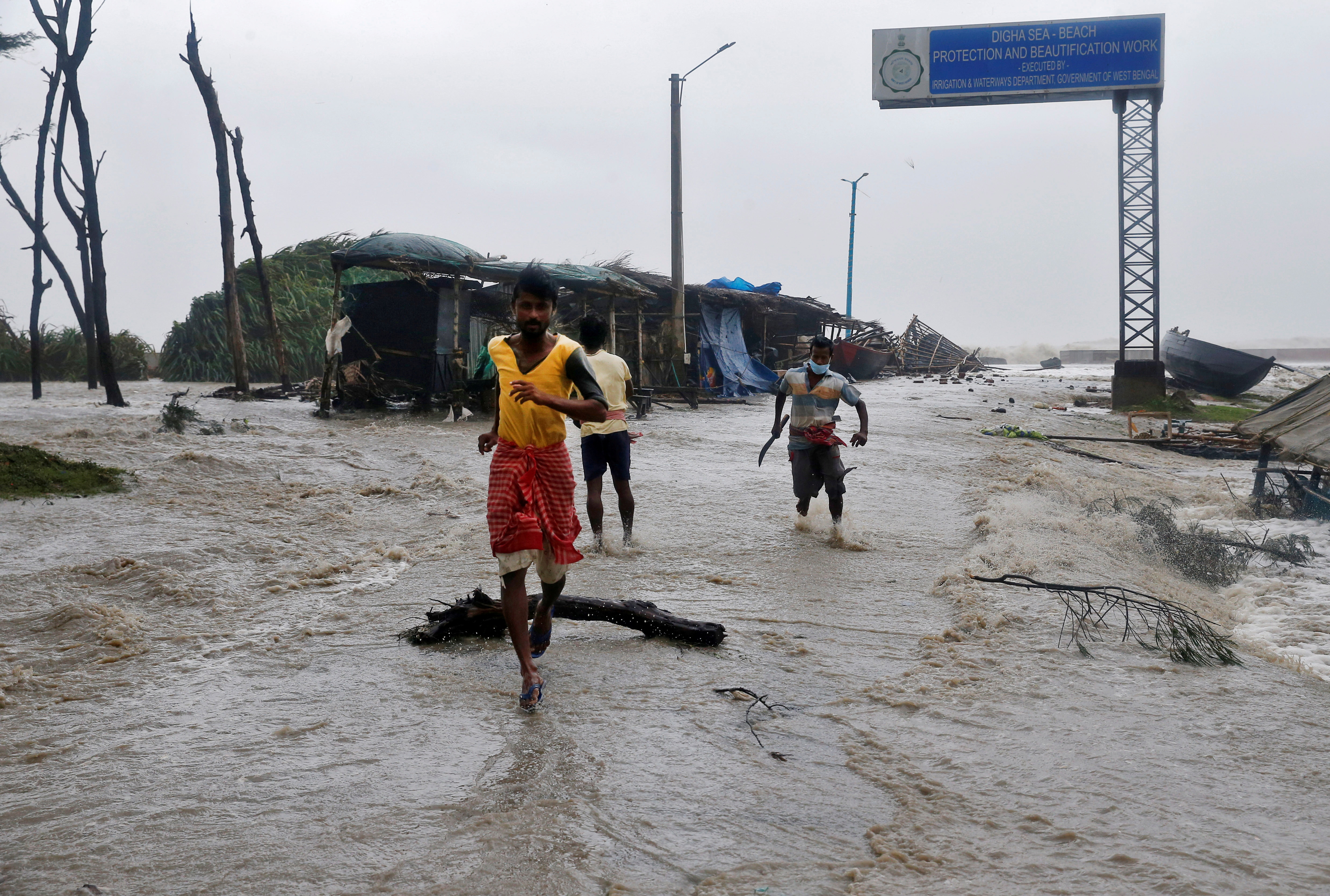 People run through a waterlogged road due to rising sea level ahead of Cyclone Yaas at Digha