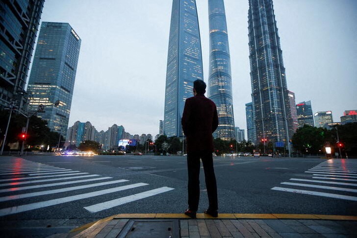 A man stands at a crossroads in Lujiazui financial district in Pudong, Shanghai