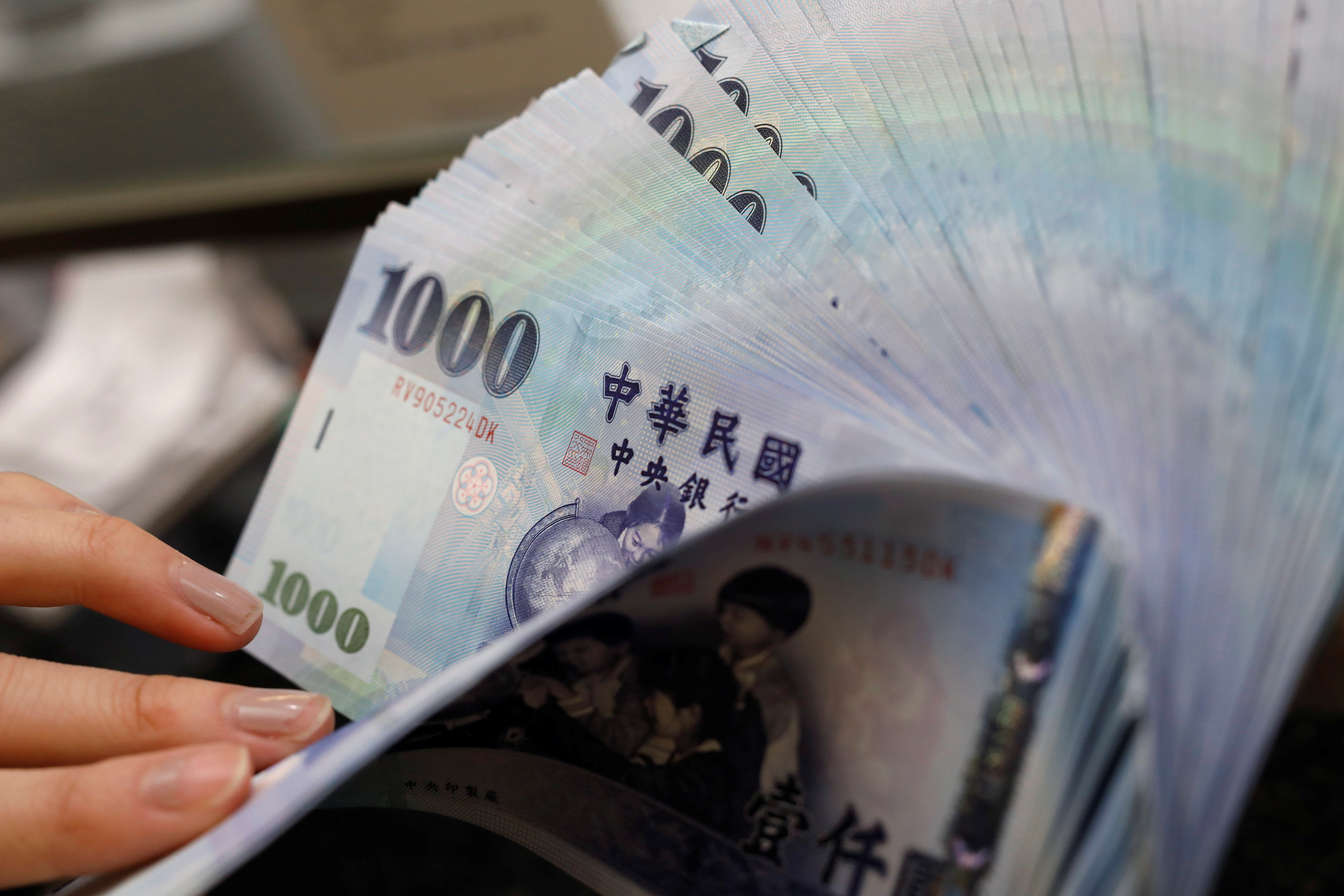 A teller counts New Taiwan dollar (TWD) $1000 banknotes at a bank in Taipei, Taiwan