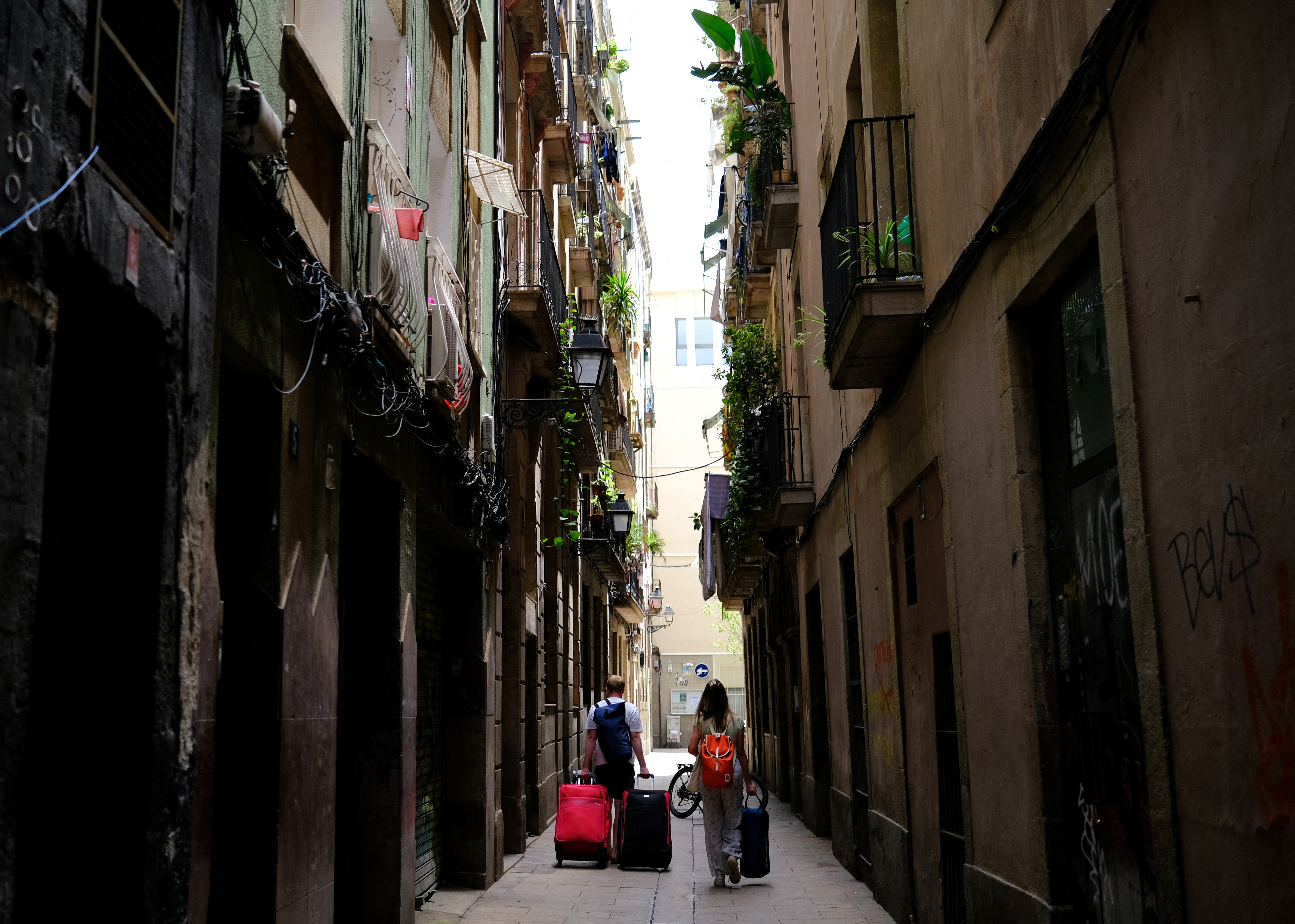 Tourists walk with their suitcases in Gothic Quarter, in Barcelona