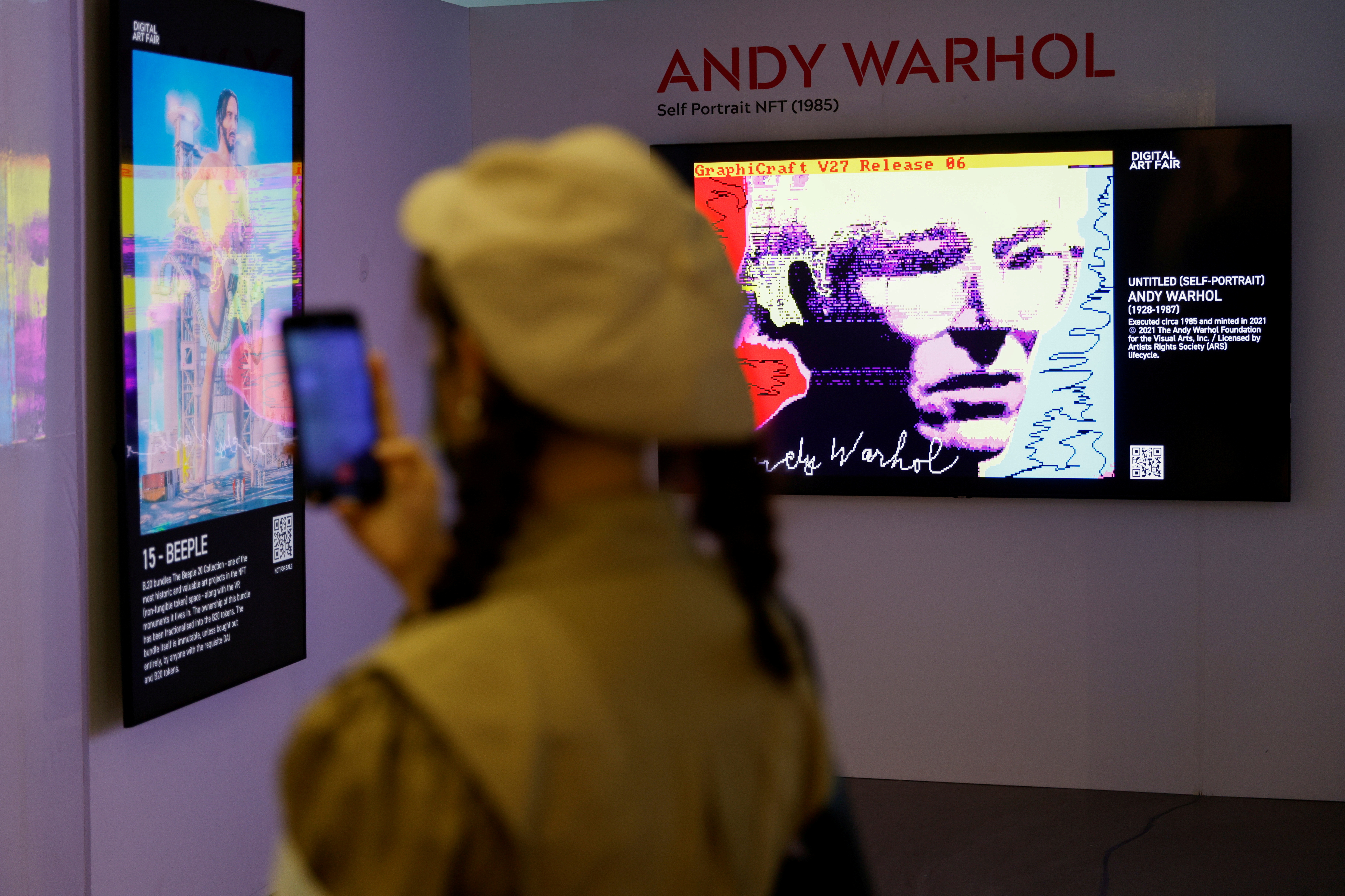 Visitor takes a photo in front of digital works at the Digital Art Fair in Hong Kong