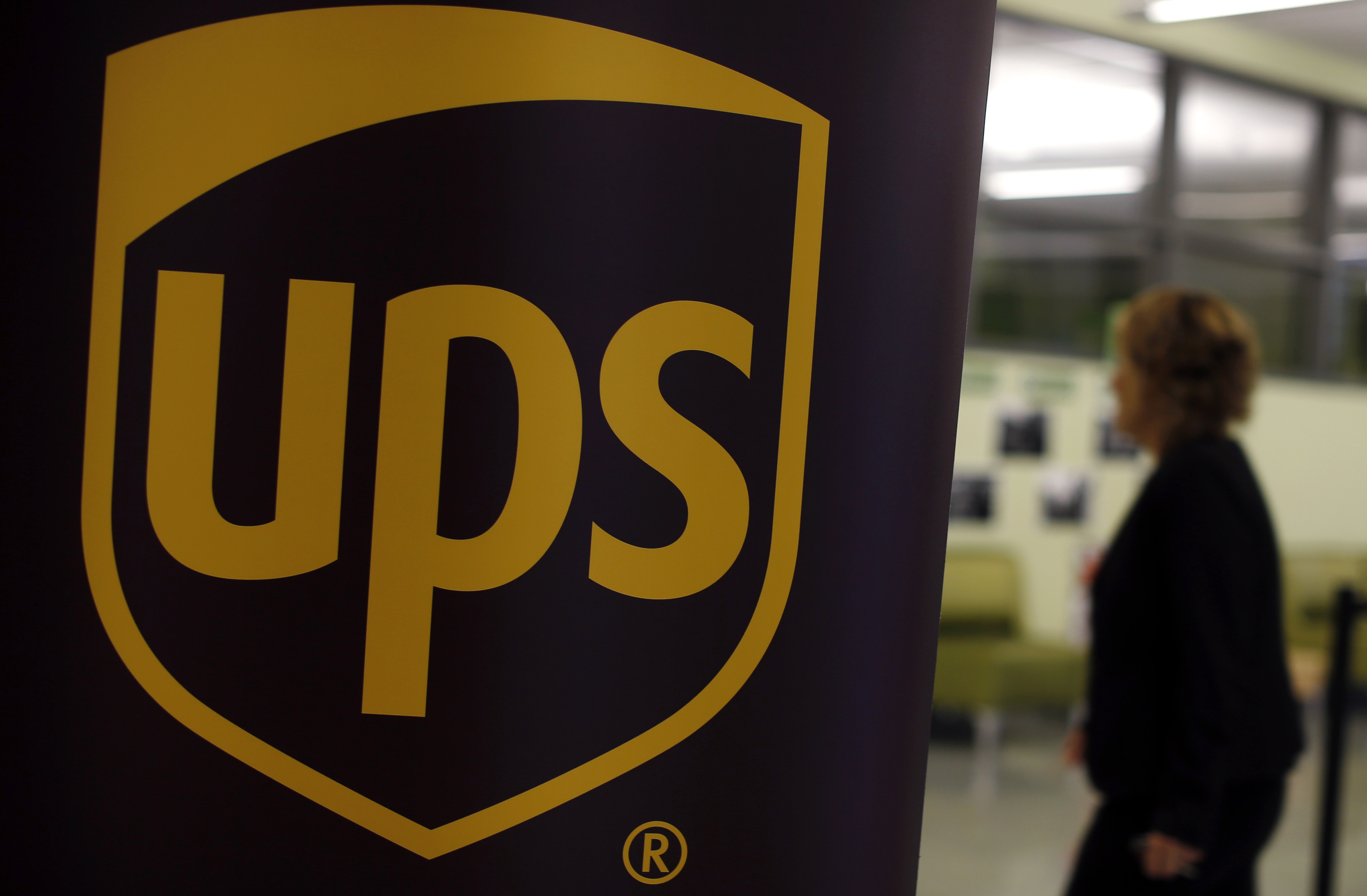 A woman walks past a sign bearing the logo of United Parcel Service (UPS) at a job fair in Chicago, Illinois, October 18, 2014. REUTERS/Jim Young 