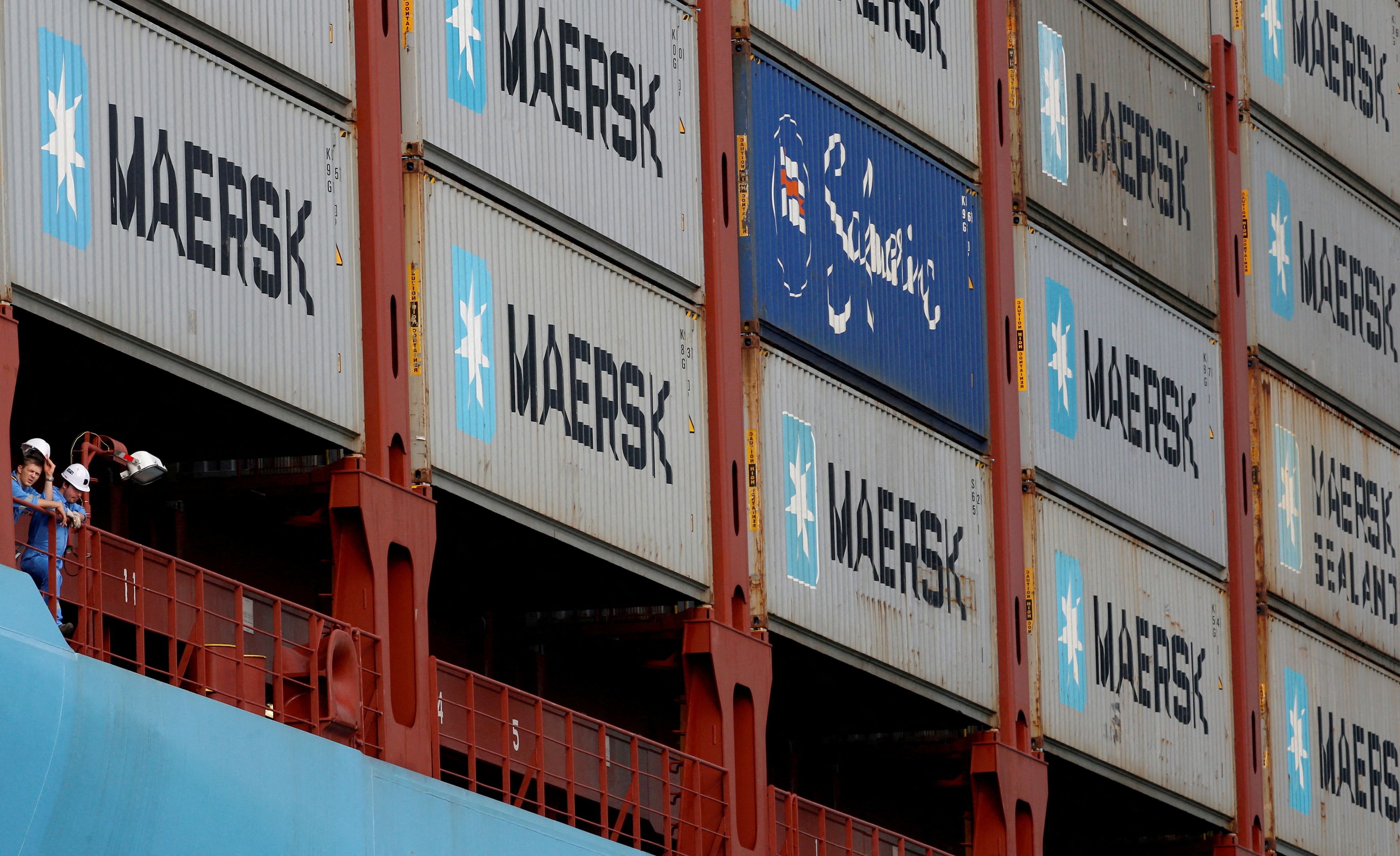 Crew members look out from the MV Maersk Mc-Kinney Moller as it berths at a PSA International port terminal in Singapore
