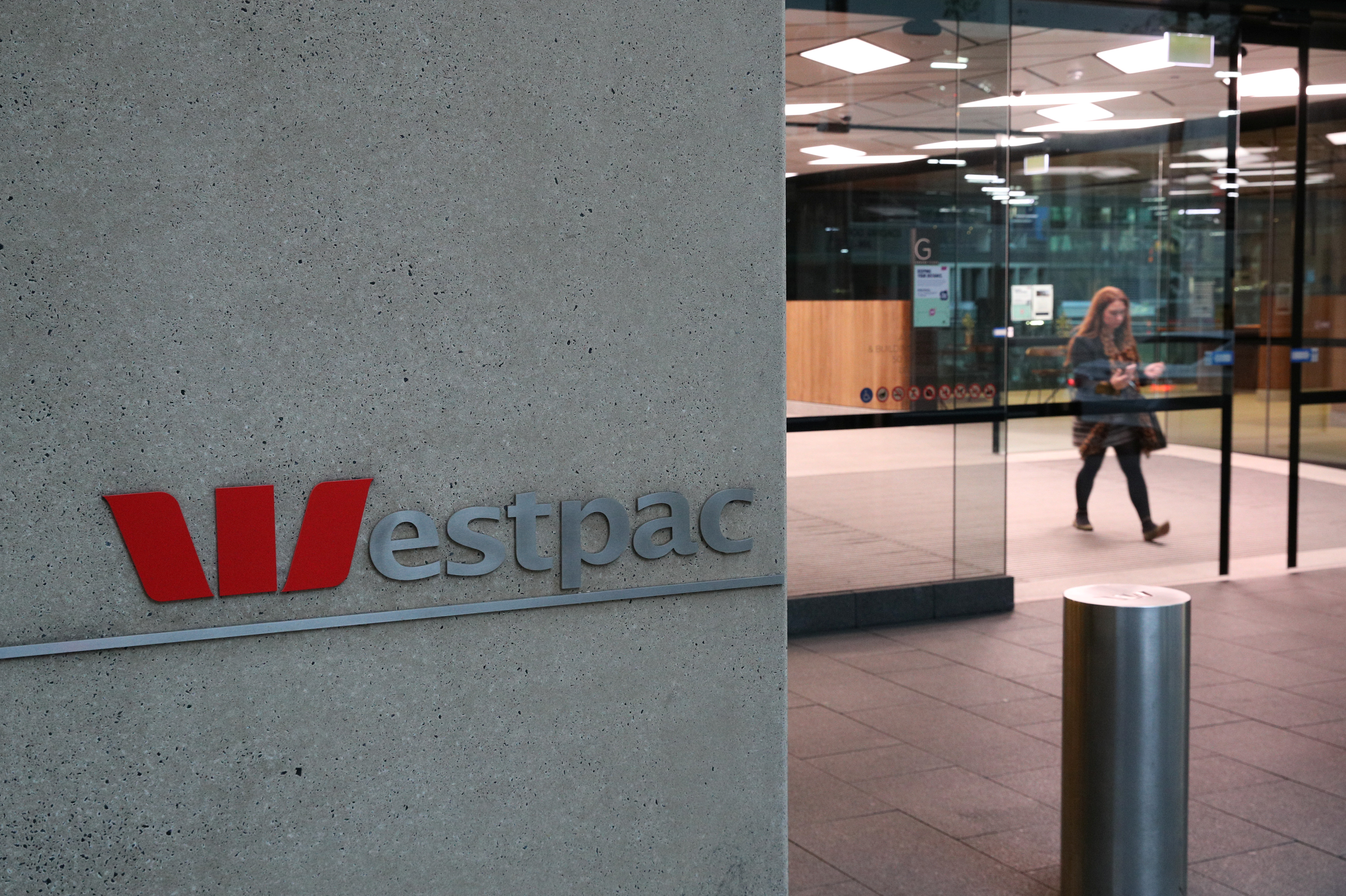 A woman exits the ground floor of an office building with Westpac logo in Sydney