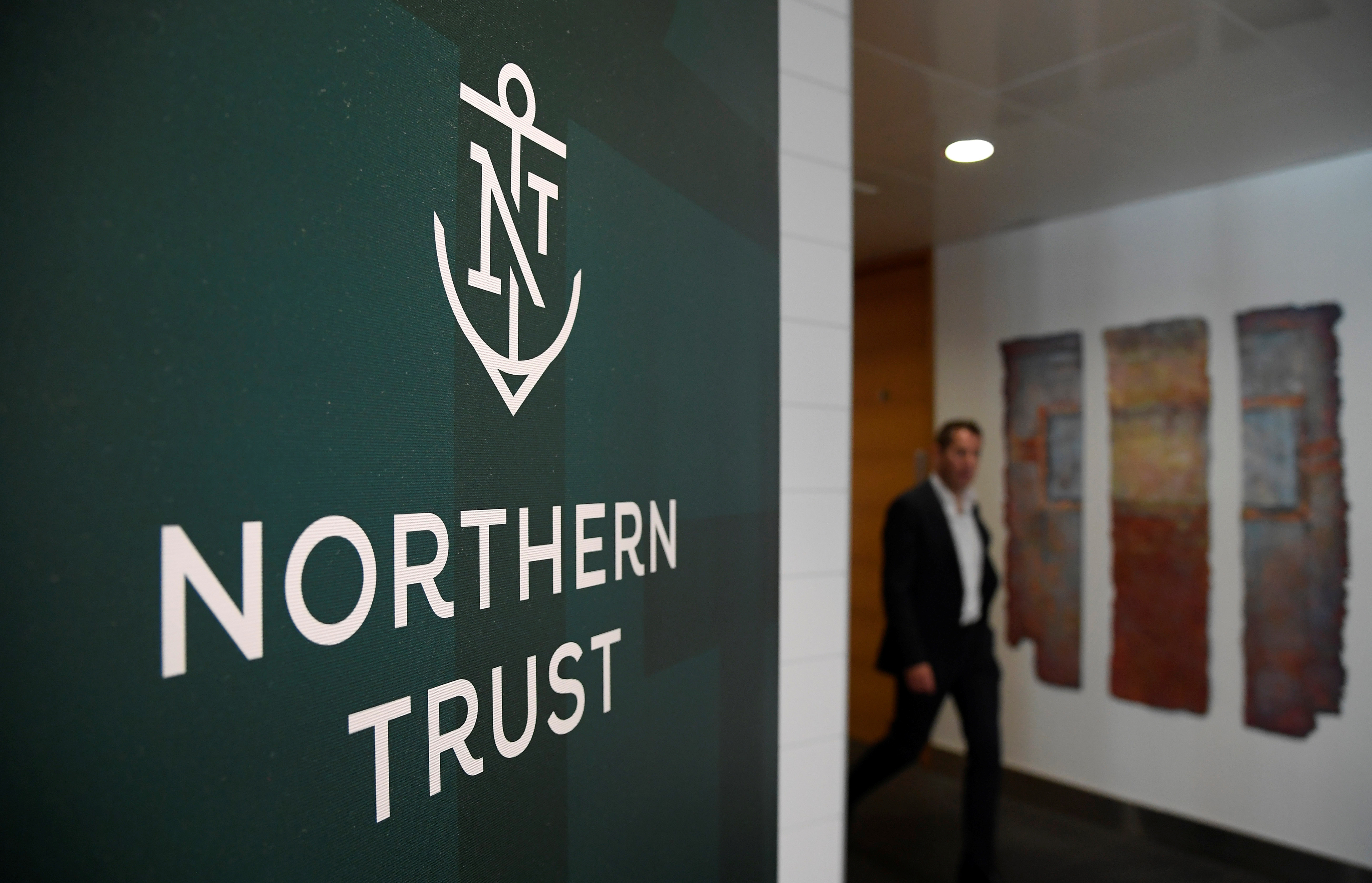 An employee walks past a company logo at Northern Trust offices in London