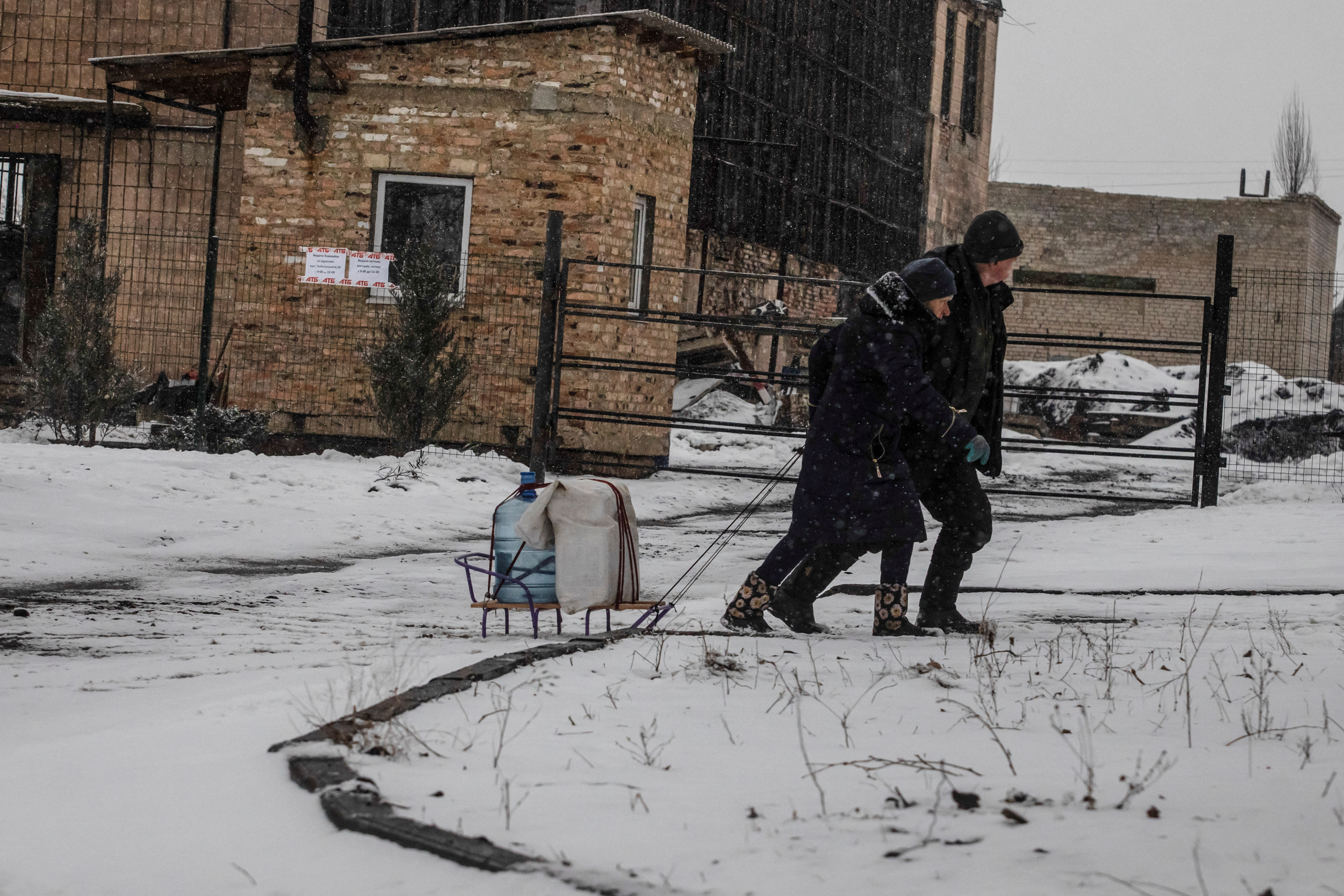 Local residents pull a sledge loaded with bottles with water in the frontline town of Bakhmut