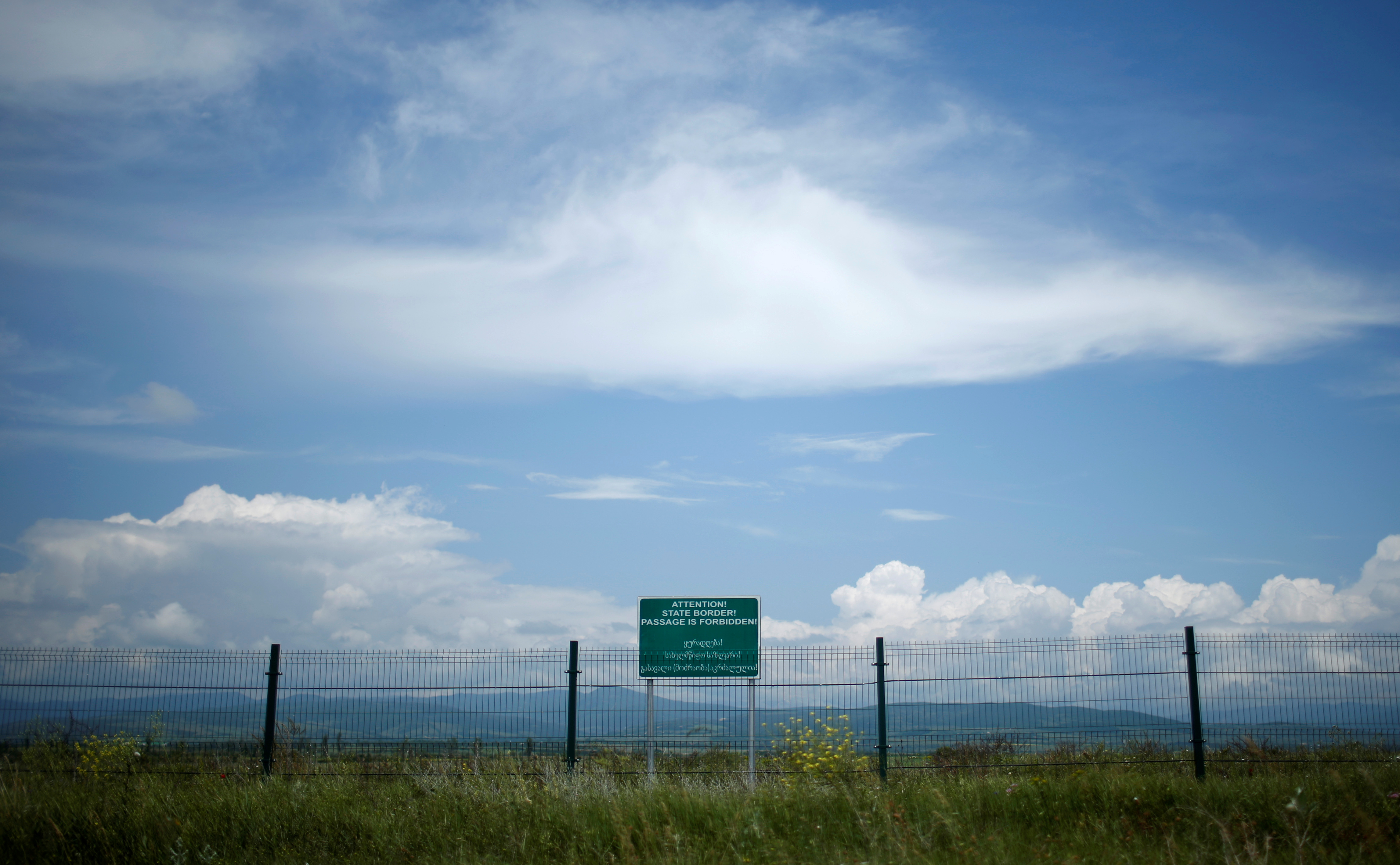 A border fence and a banner are seen on the de facto border of Georgia's breakaway region of South Ossetia near Dvani