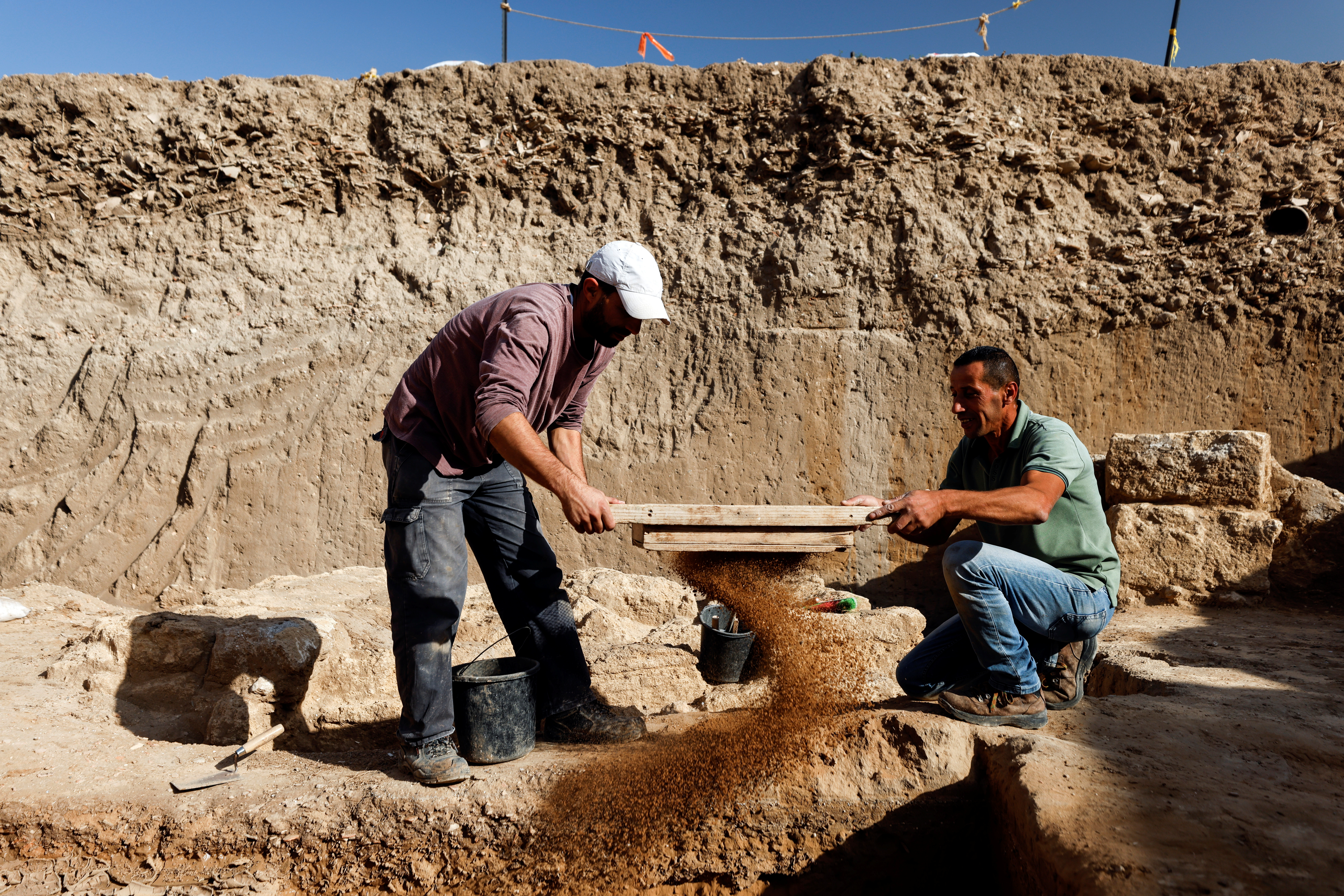 Workers use a sieve at the site of an excavation believed to be from the time of the Sanhedrin, the late first and second centuries CE according to the Israel Antiquities Authority, in Yavne, Israel November 29, 2021. REUTERS/Amir Cohen