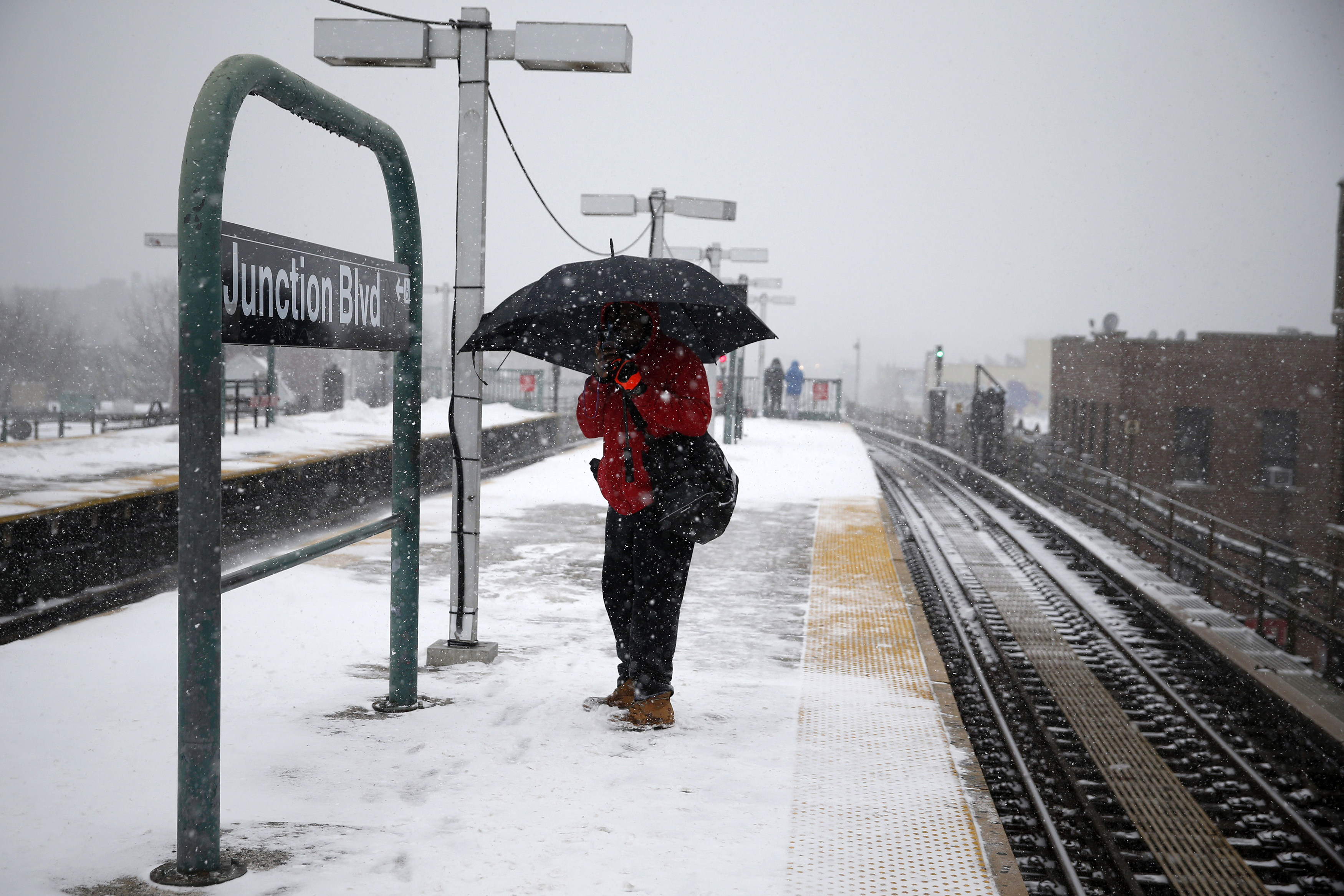A man stands with an umbrella at the Junction Boulevard stop of the 7 subway train line in the Queens borough of New York