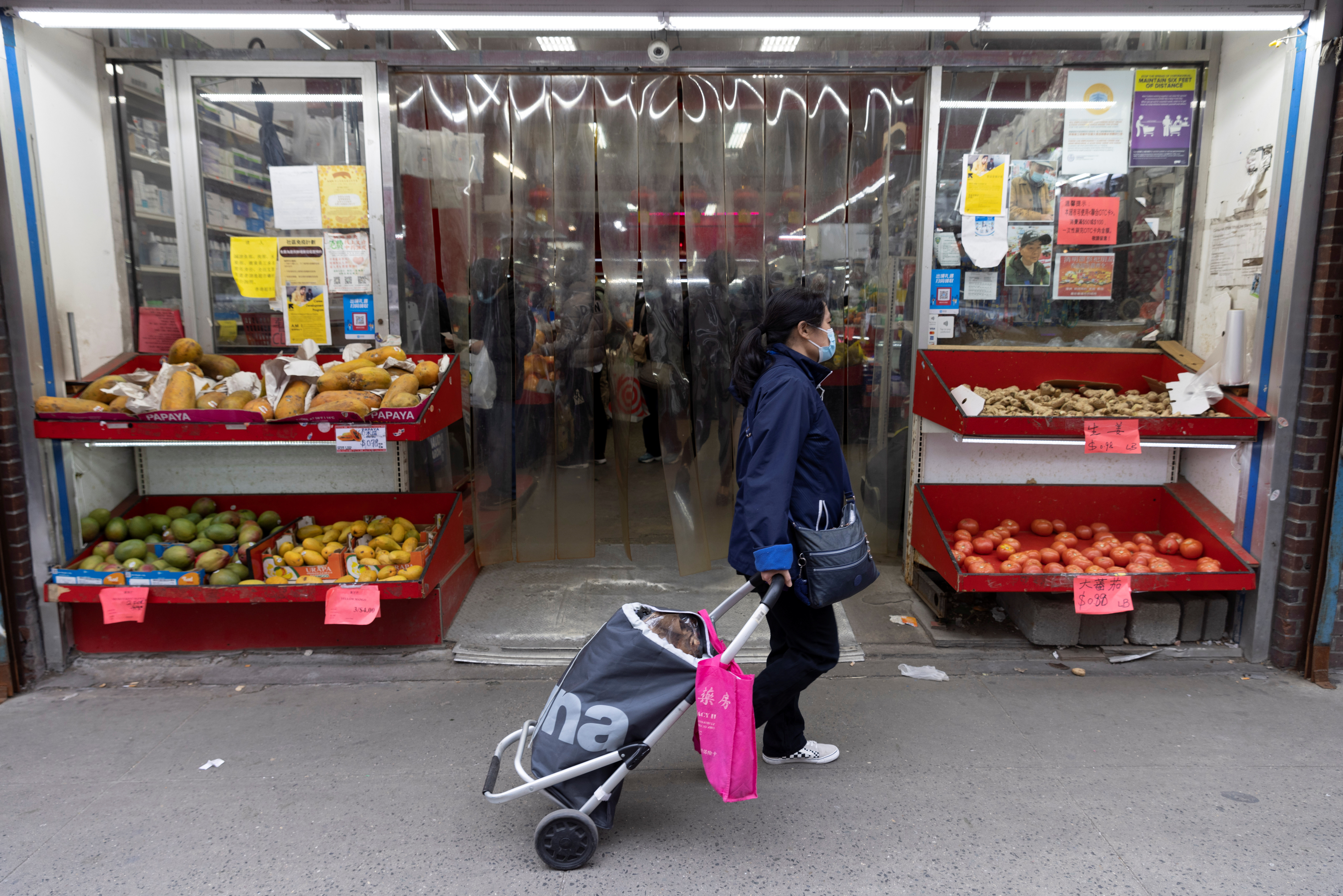 A person walks past a grocery store in Manhattan, New York City