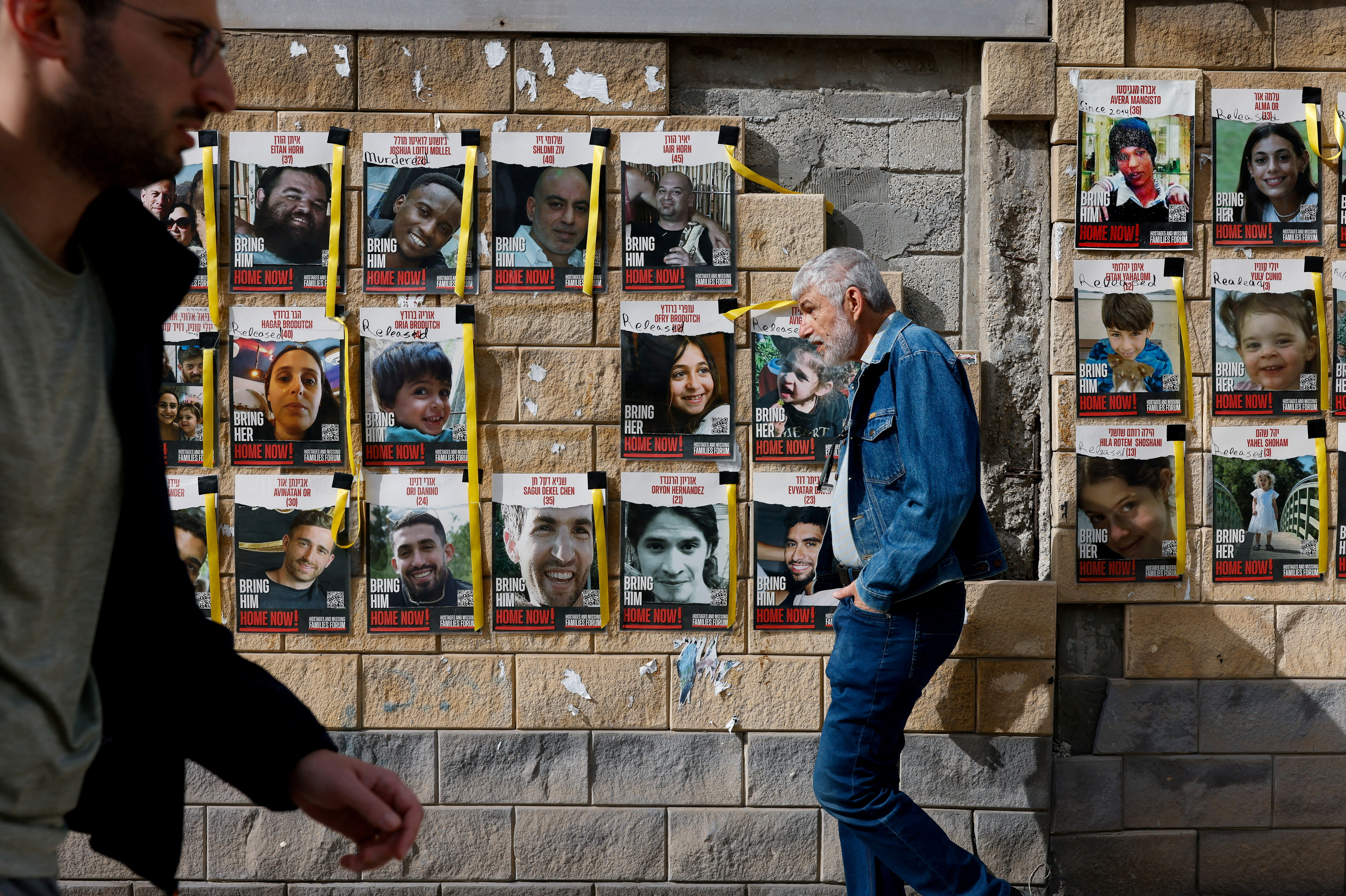 People walk past posters with photos of hostages, in Tel Aviv