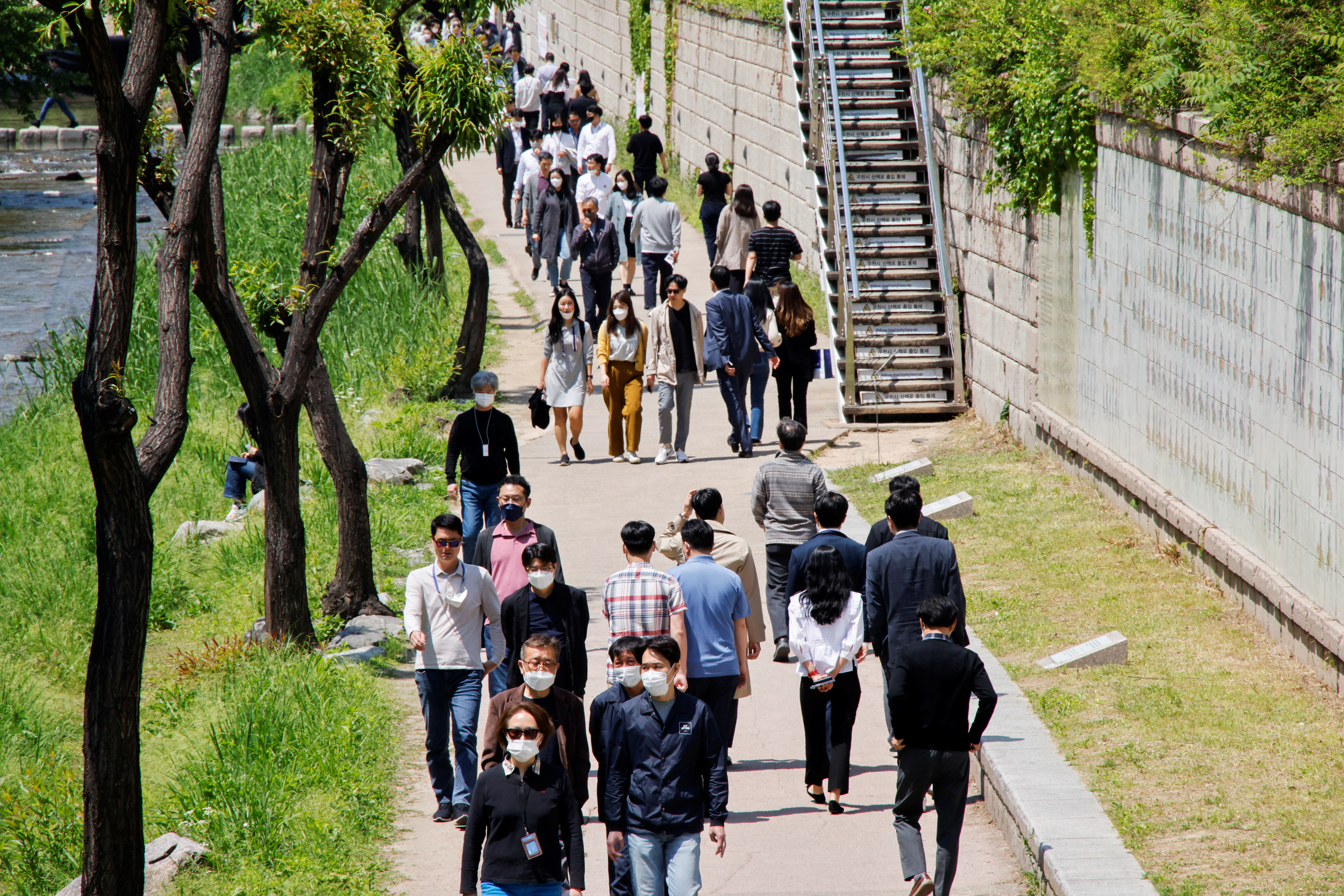 People wear masks to prevent the spread of the coronavirus disease (COVID-19) as they take a walk on a sunny spring day in Seoul
