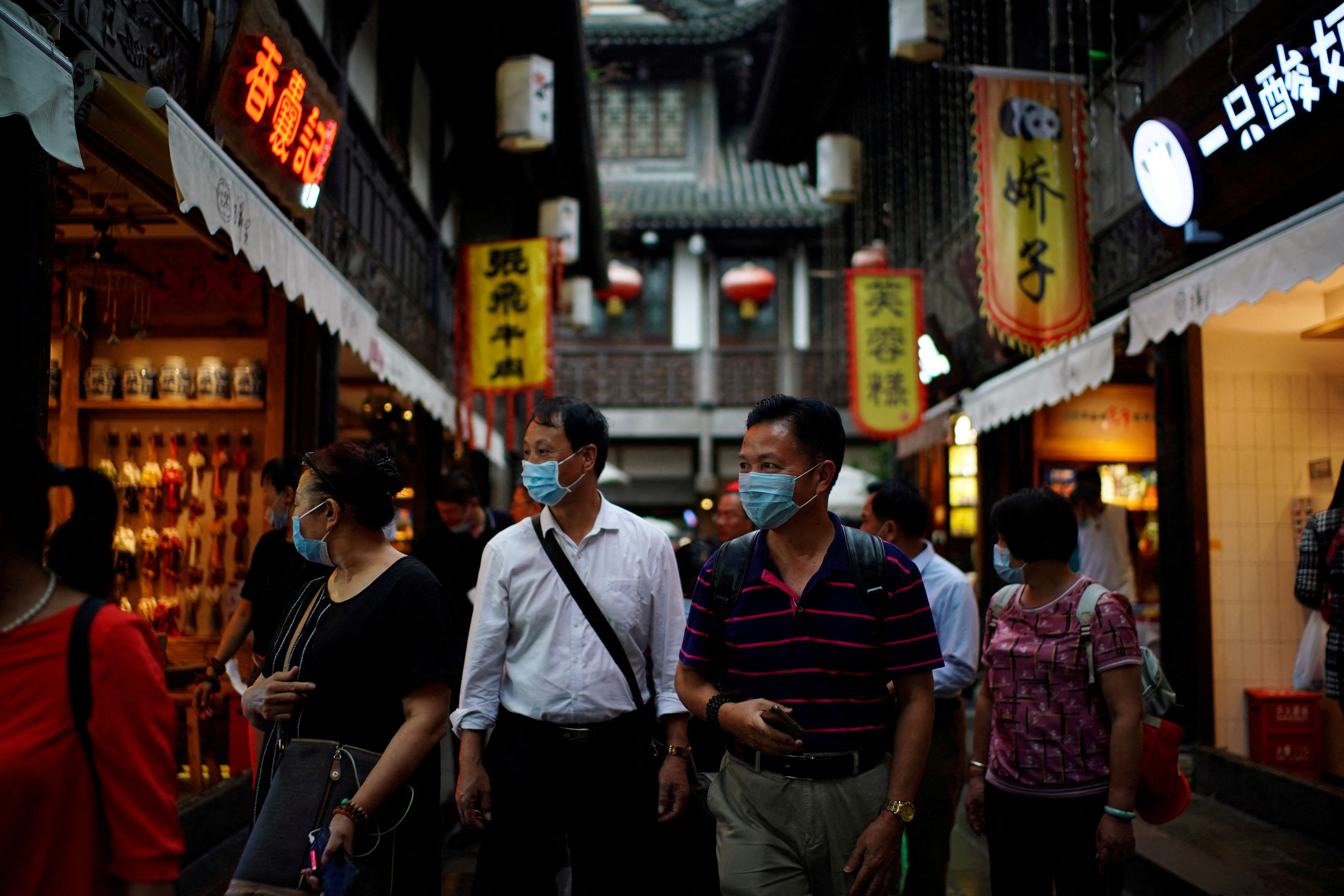 People wearing face masks walk on Jinli Ancient Street in Chengdu