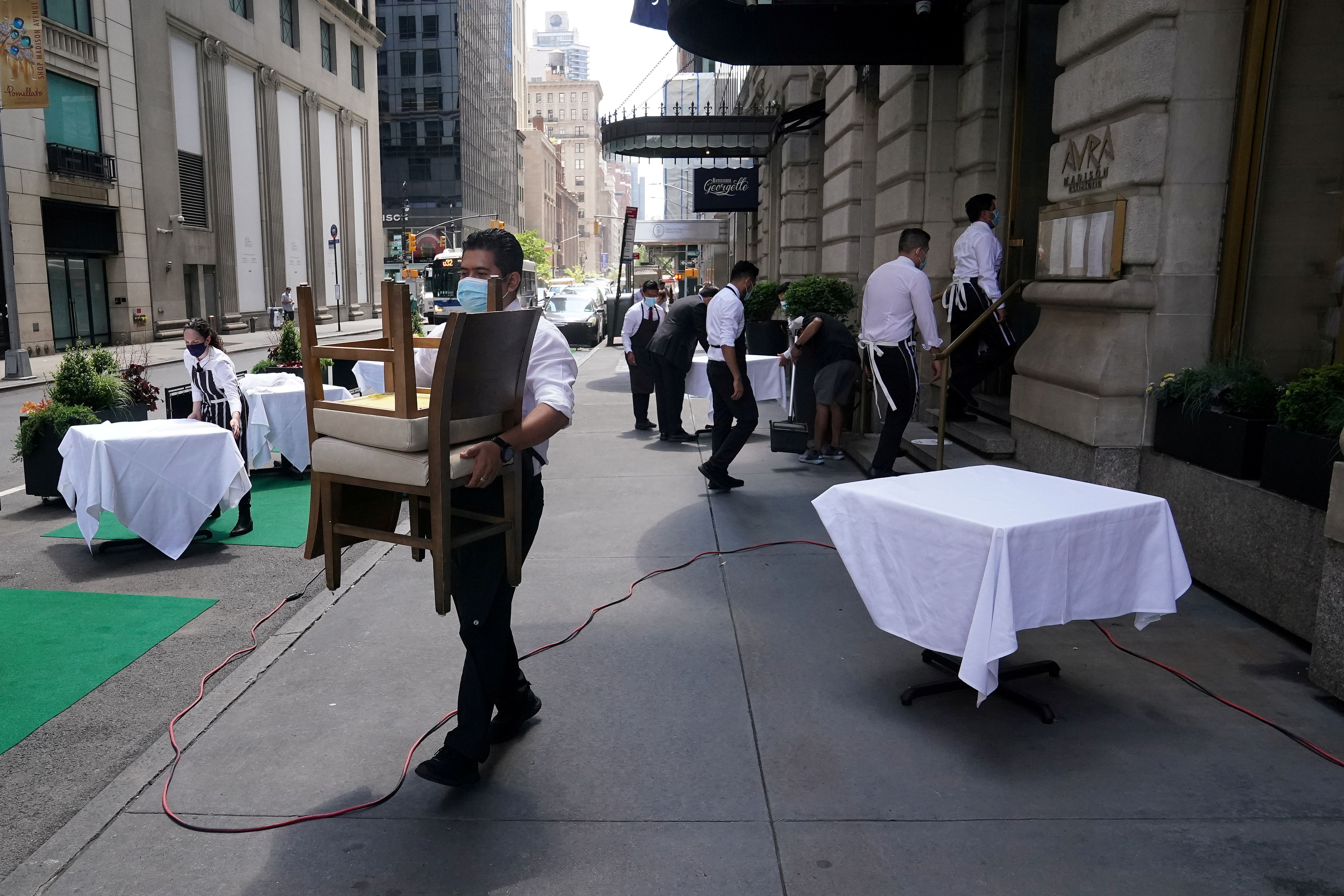 A waiter sets up tables in front of a restaurant on a street on the first day of the phase two re-opening of businesses following the outbreak of the coronavirus disease (COVID-19), in the Manhattan borough of New York City