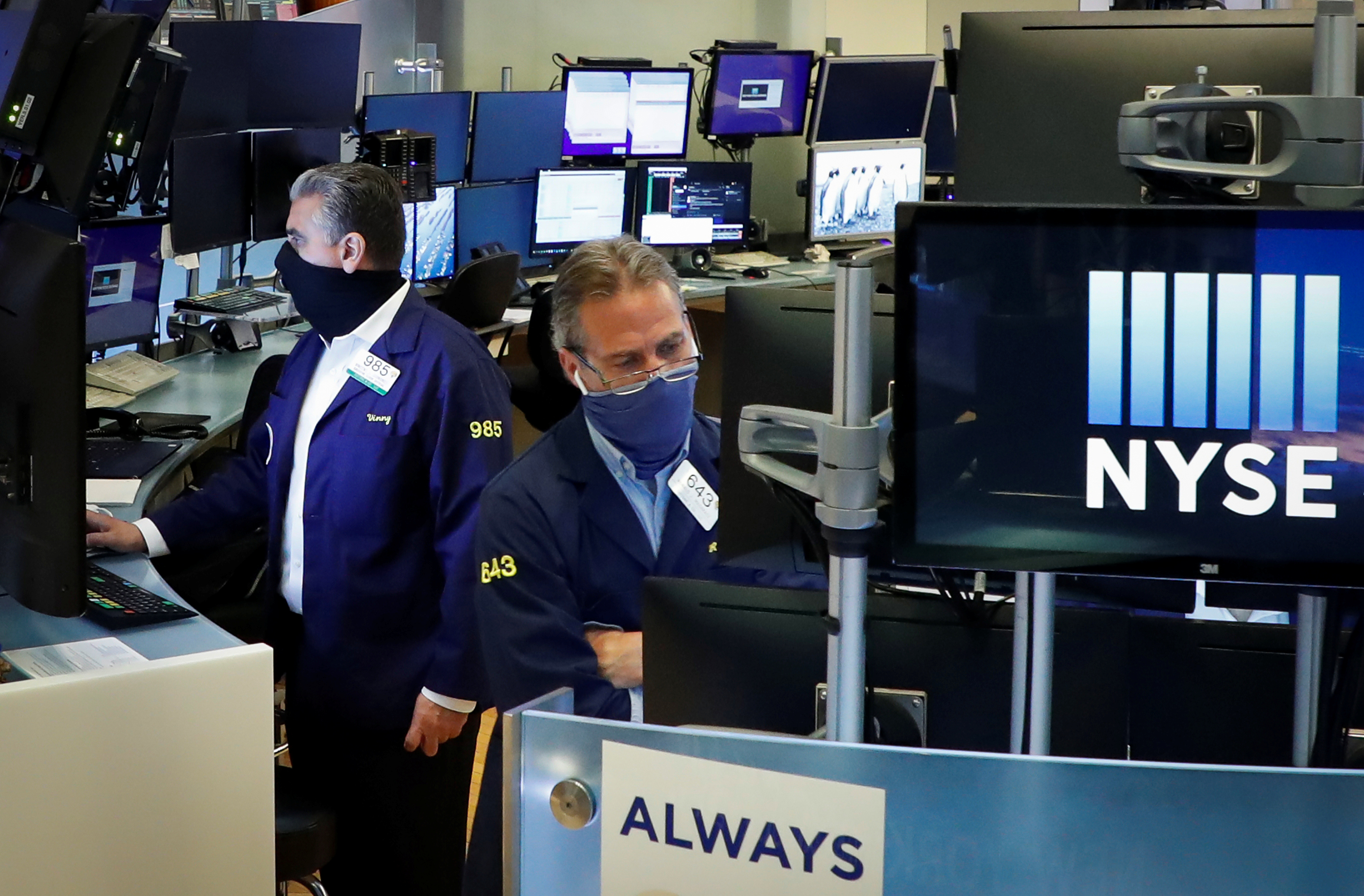 Traders wearing masks work, on the first day of in person trading since the closure during the outbreak of the coronavirus disease (COVID-19) on the floor at the NYSE in New York
