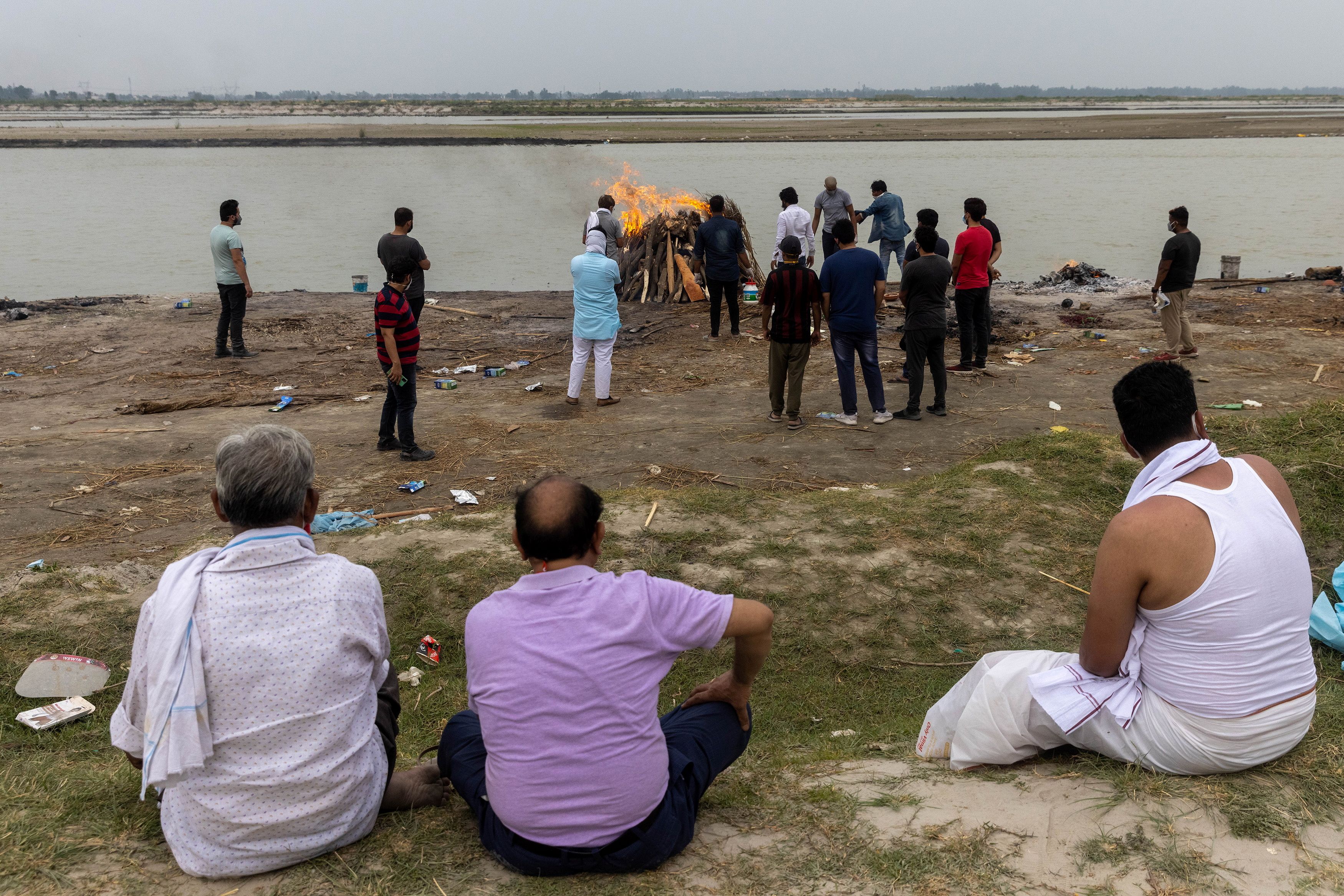 Relatives watch during the cremation of a man who died from the coronavirus disease (COVID-19), on the banks of the river Ganges at Garhmukteshwar in the northern state of Uttar Pradesh