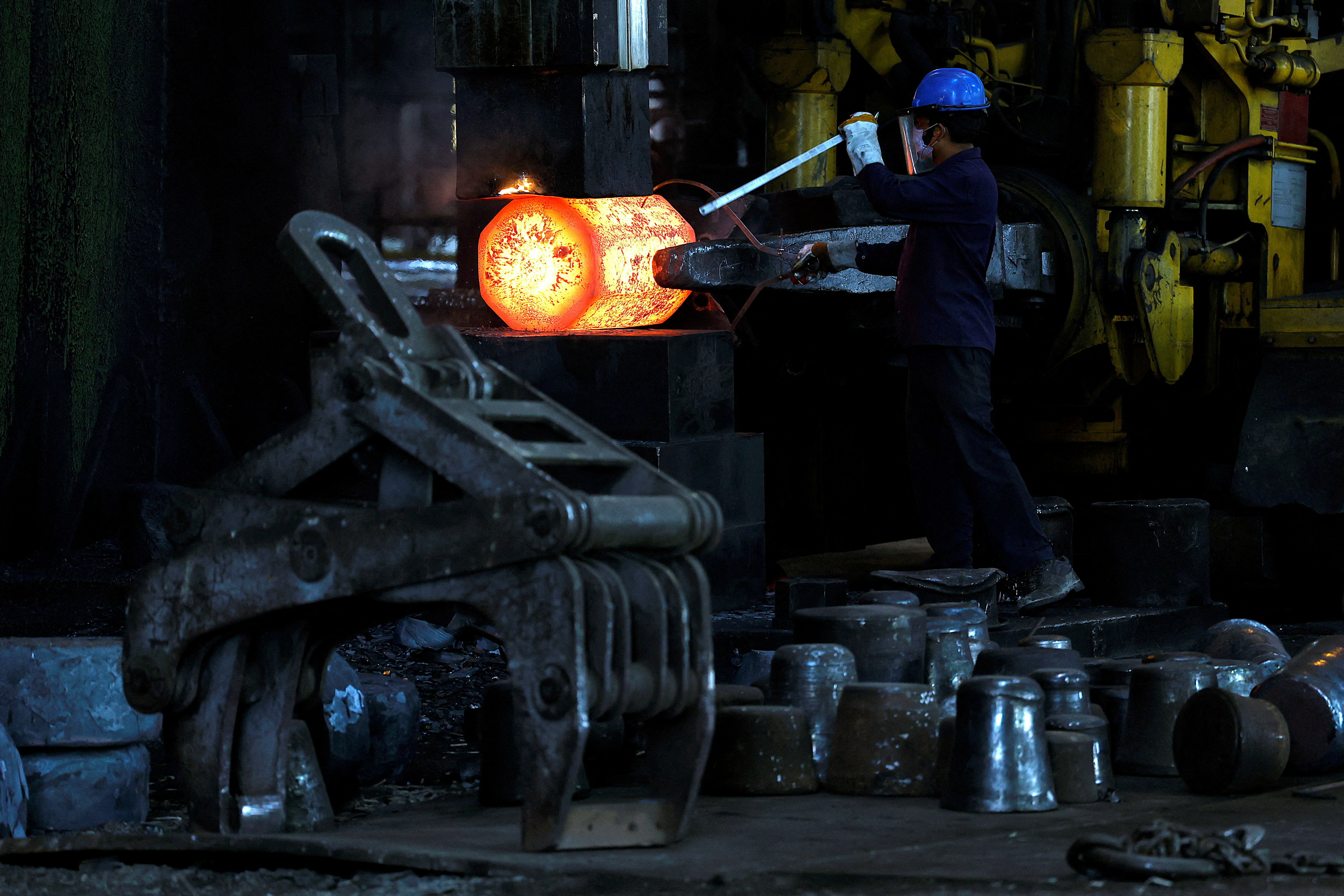 An employee moves forging red hot steel inside the ArcVac ForgeCast factory, in Hooghly district