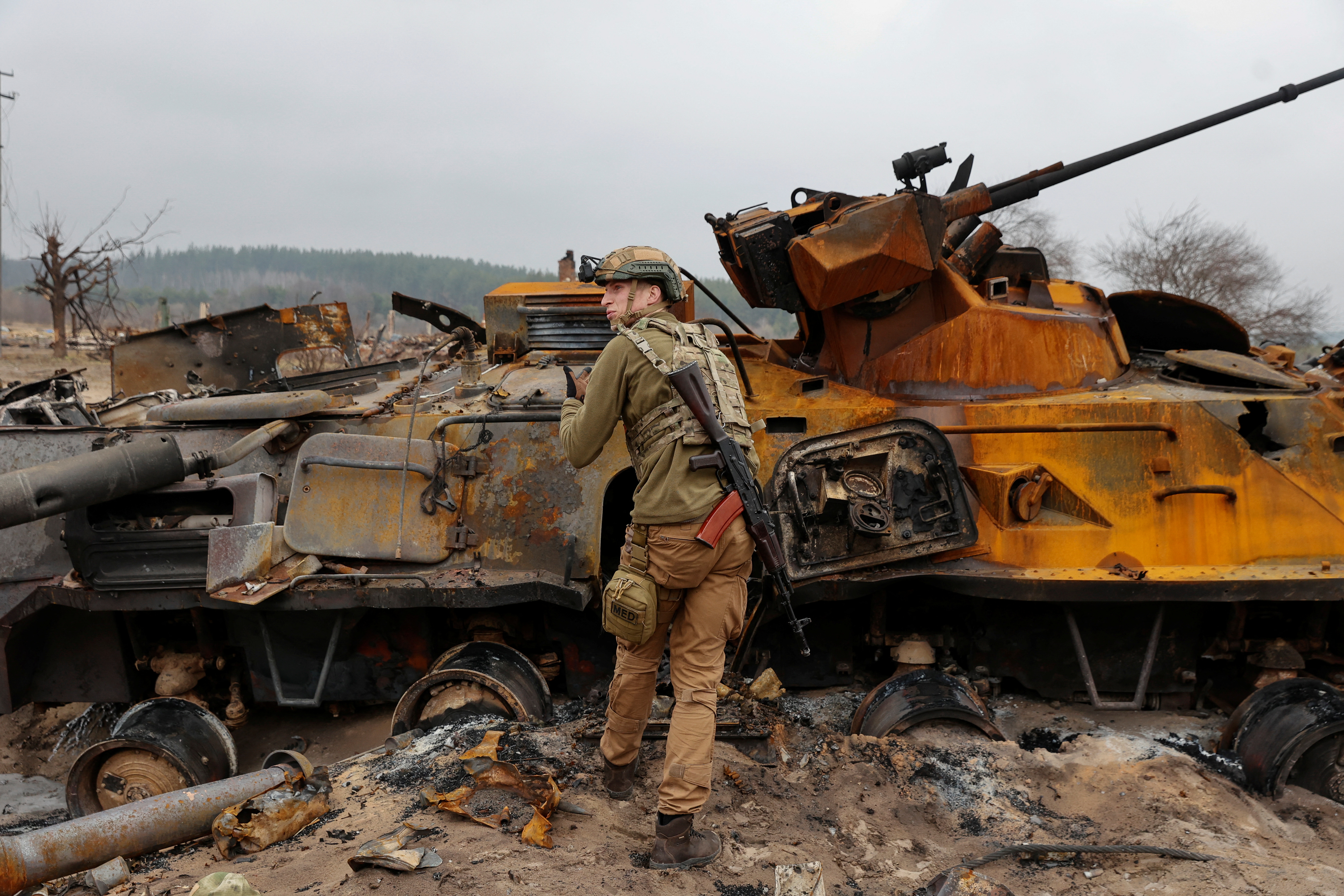 A Ukrainian service member inspects destroyed Russian BTR-82 in a village near a frontline in Kyiv Region