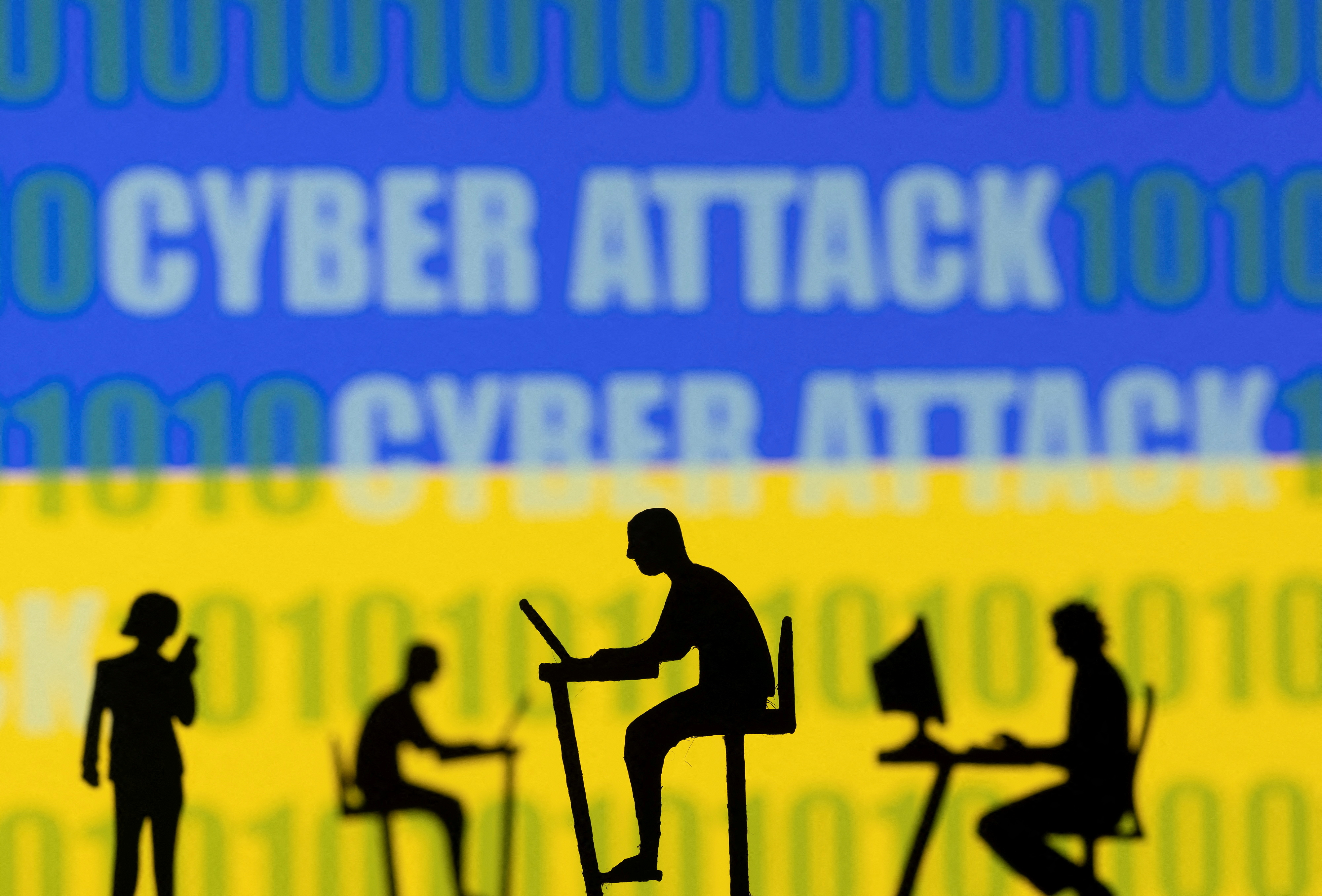 Figurines with computers and smartphones are seen in front of the words "Cyber Attack", binary codes and the Ukrainian flag, in this illustration taken February 15, 2022. REUTERS/Dado Ruvic/Illustration/File Photo