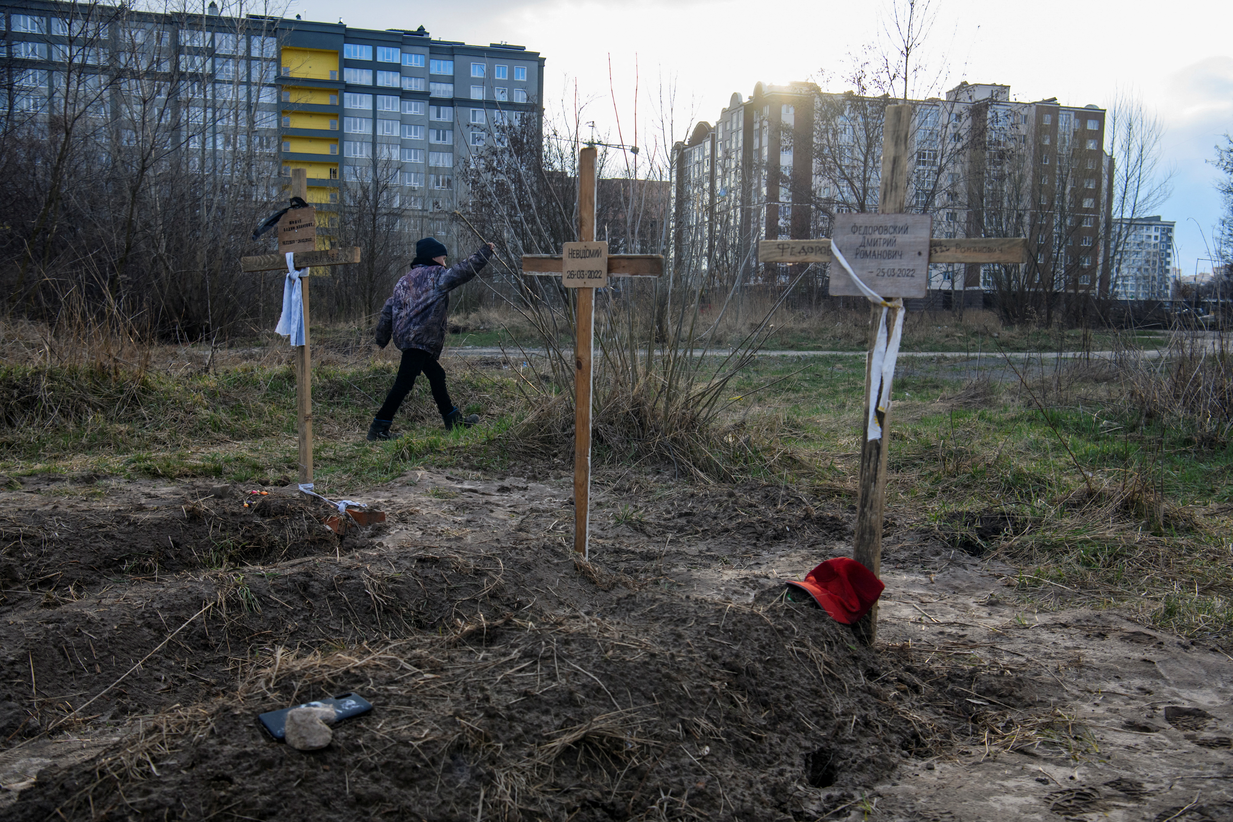 A boy walks past graves with bodies of civilians, who according to local residents were killed by Russian soldiers, in Bucha
