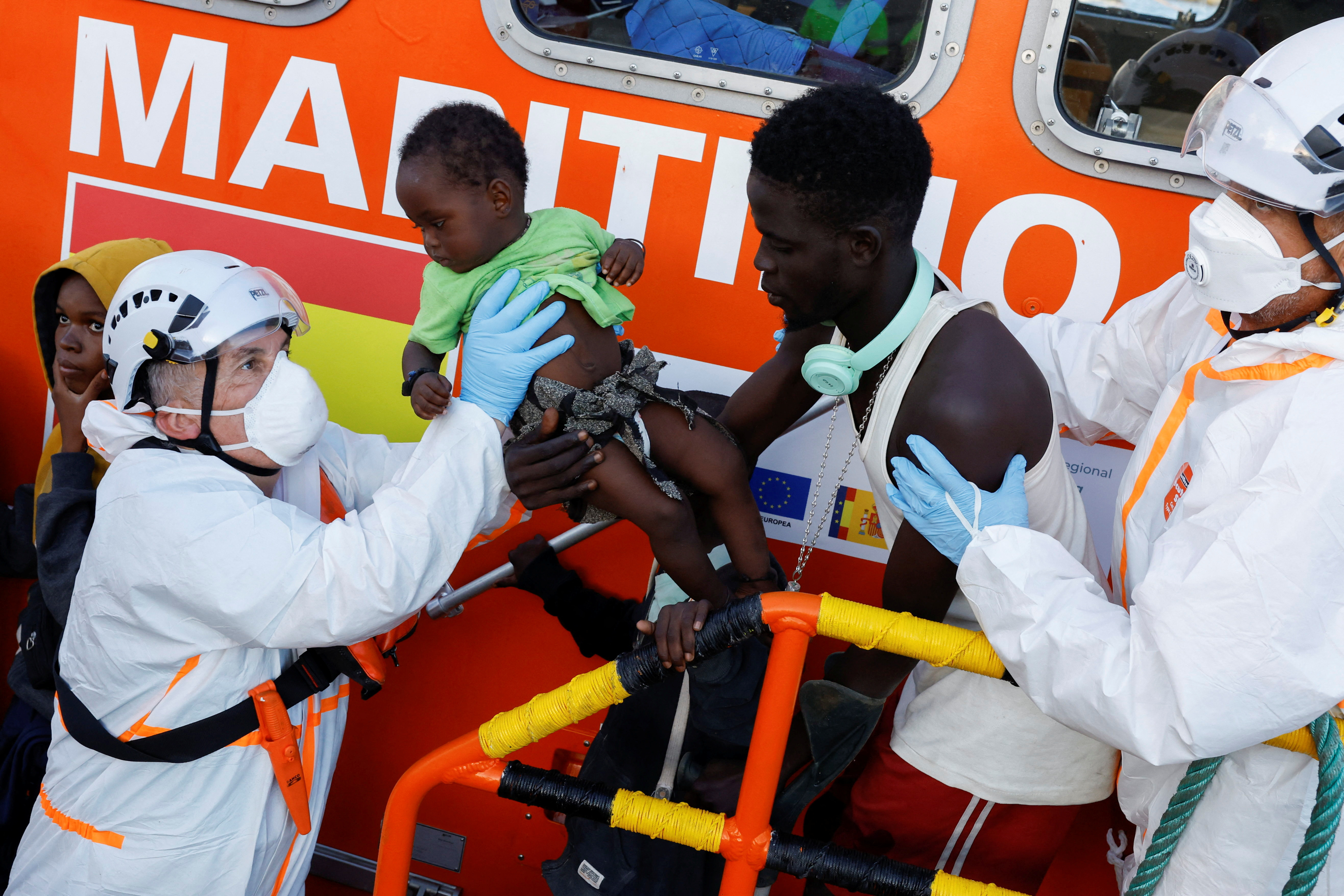 Rescuers disembark a migrant baby from a Spanish coast guard vessel, in the port of Arguineguin