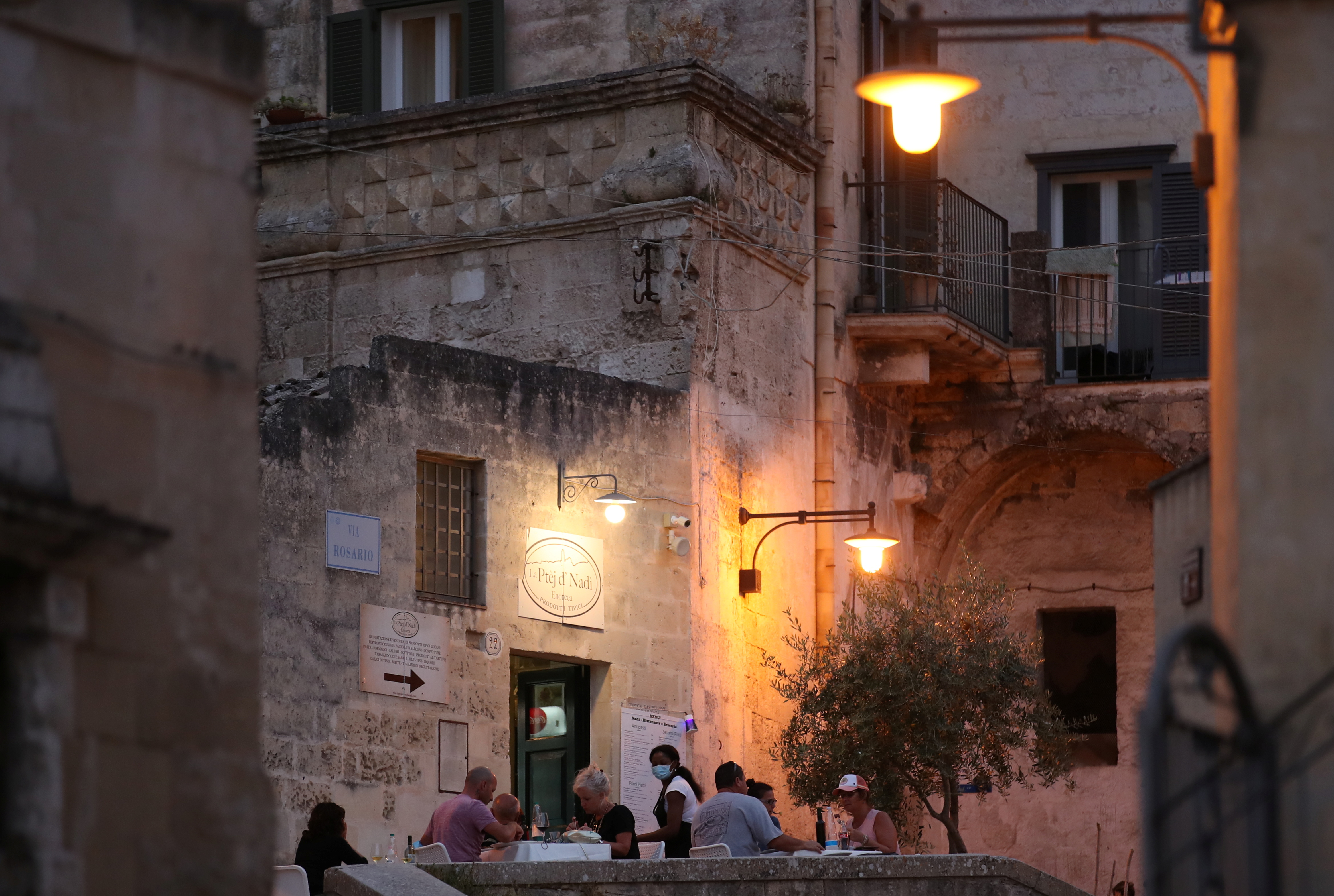 People enjoy the evening at a restaurant in Matera, Italy