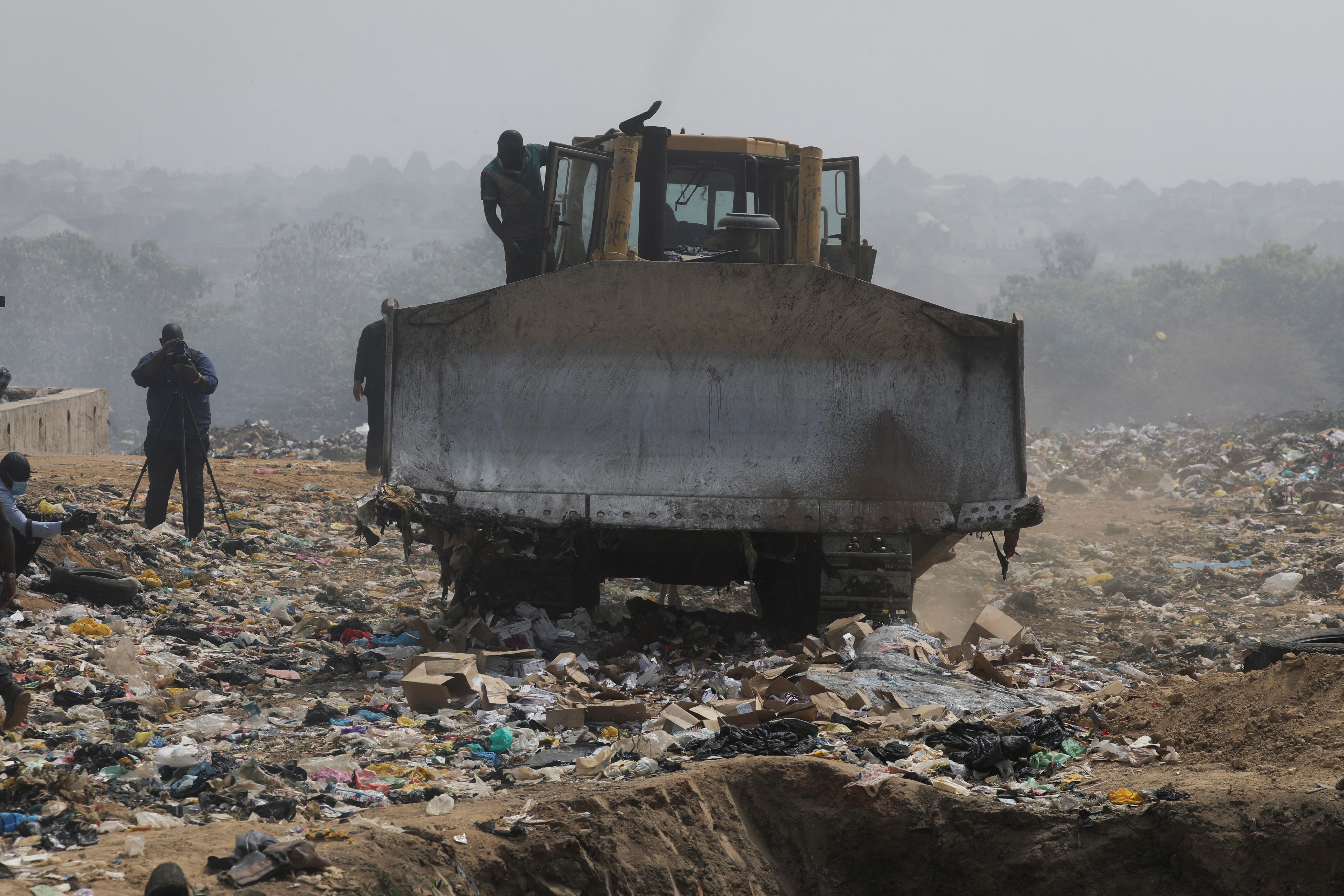 A caterpillar machine drives over expired AstraZeneca Covid-19 vaccines at the Gosa dump site in Abuja