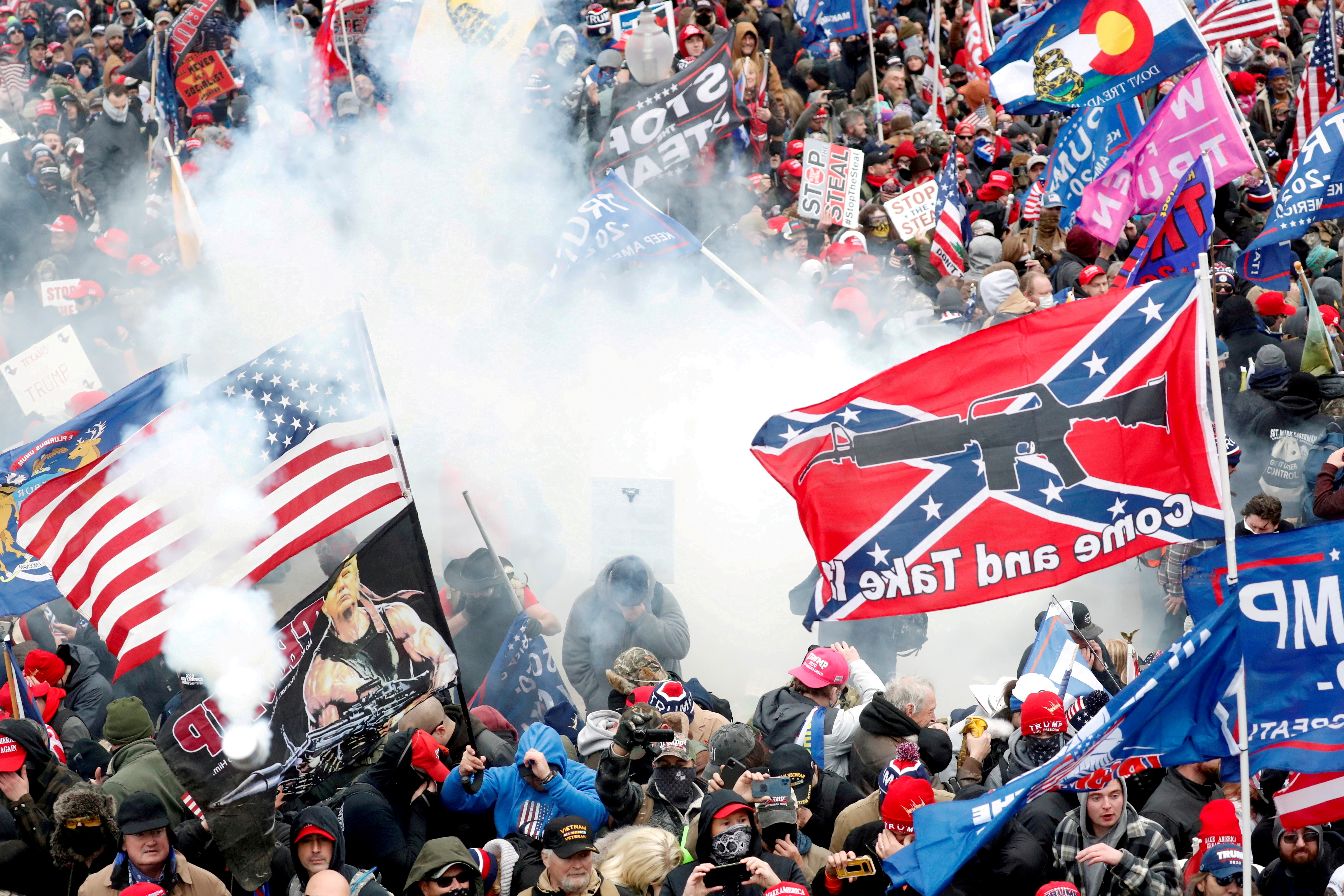 Tear gas is released into a crowd of protesters, with one wielding a Confederate battle flag that reads 