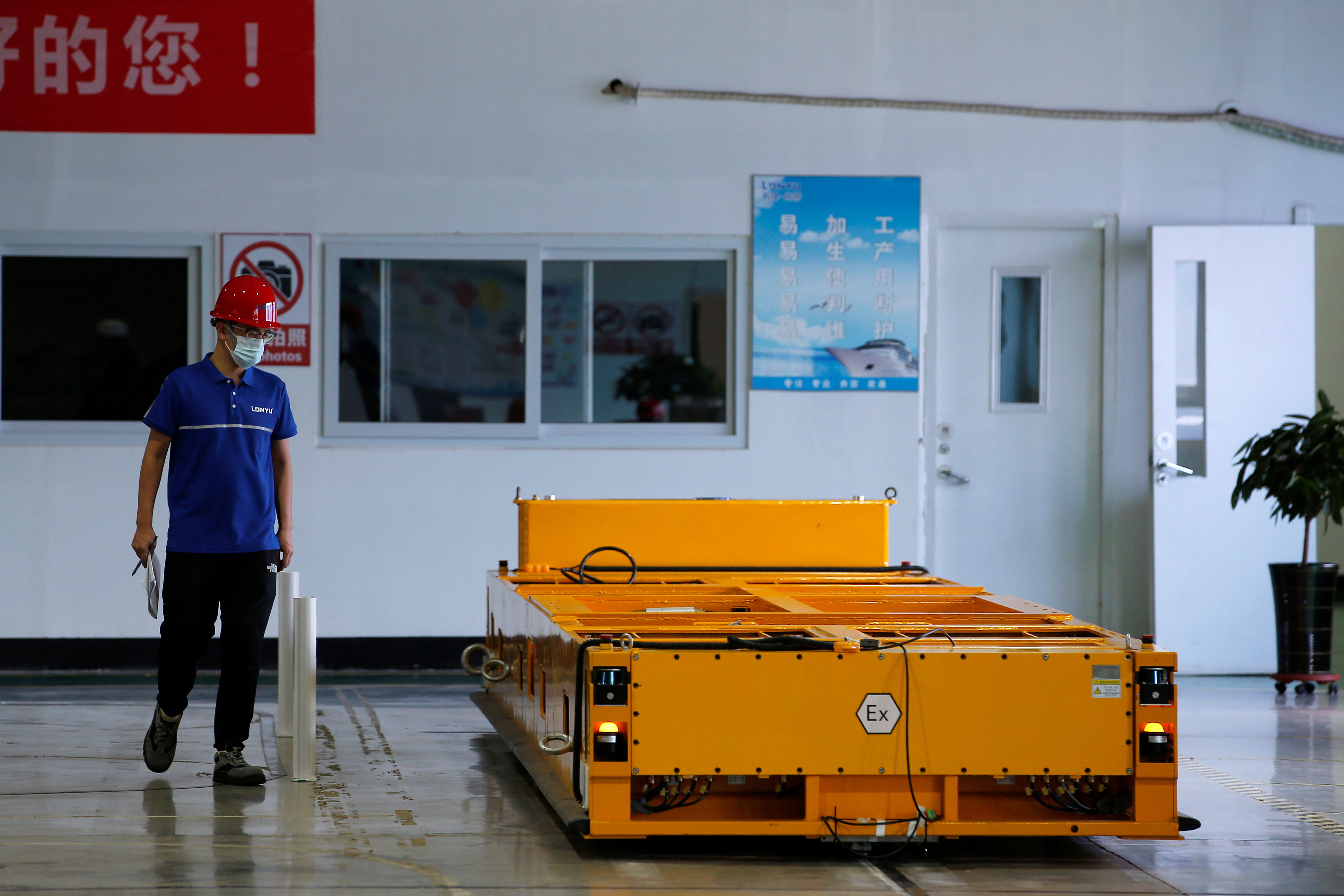 An employee inspects an automated guided vehicle (AGV) at Lonyu Robot Co in Tianjin