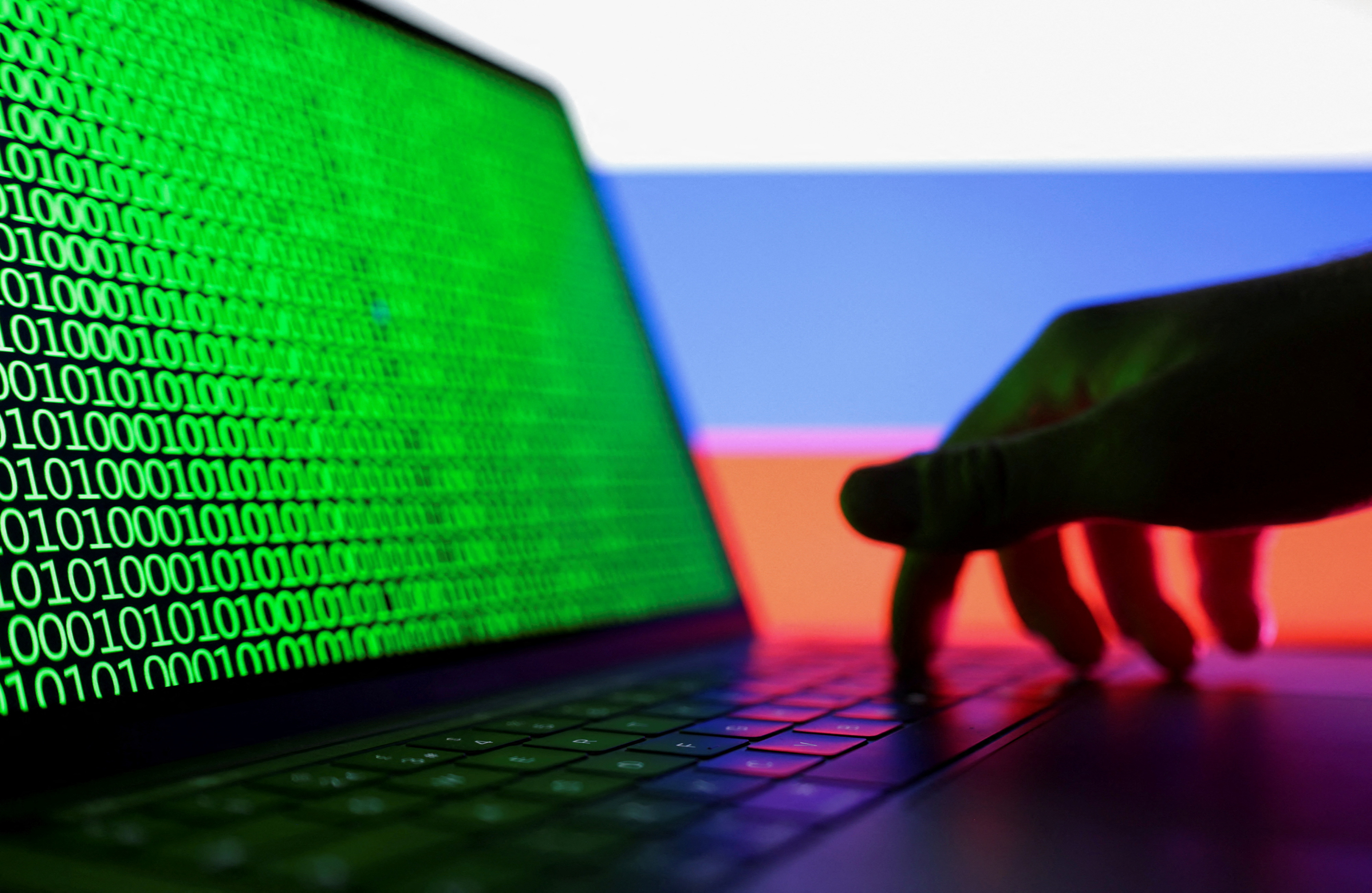Illustration shows laptop with binary code on the screen in front of Russian flag