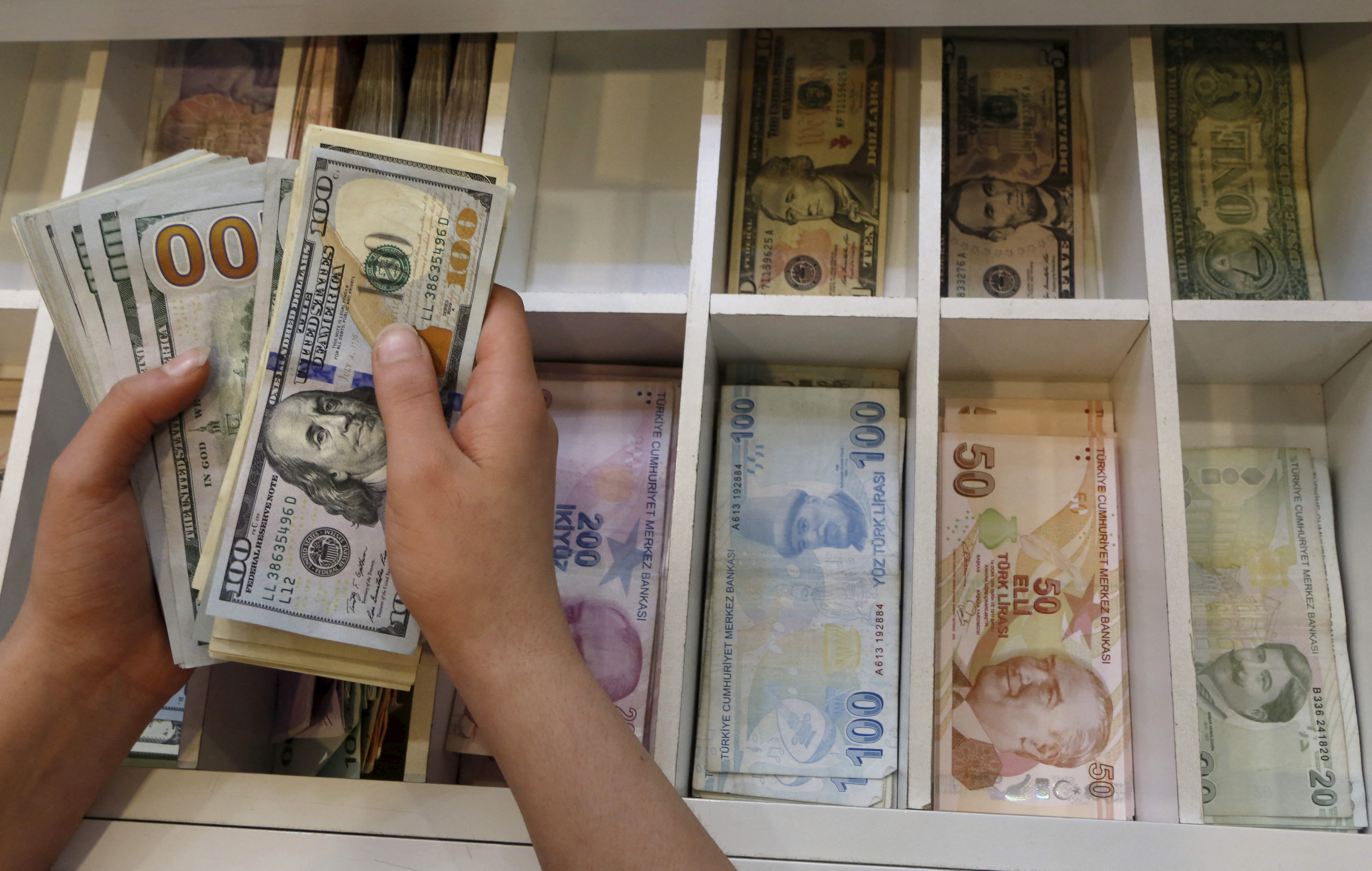 A money changer counts U.S. dollar bills, with Turkish lira banknotes in the background, at an currency exchange office in central Istanbul, Turkey