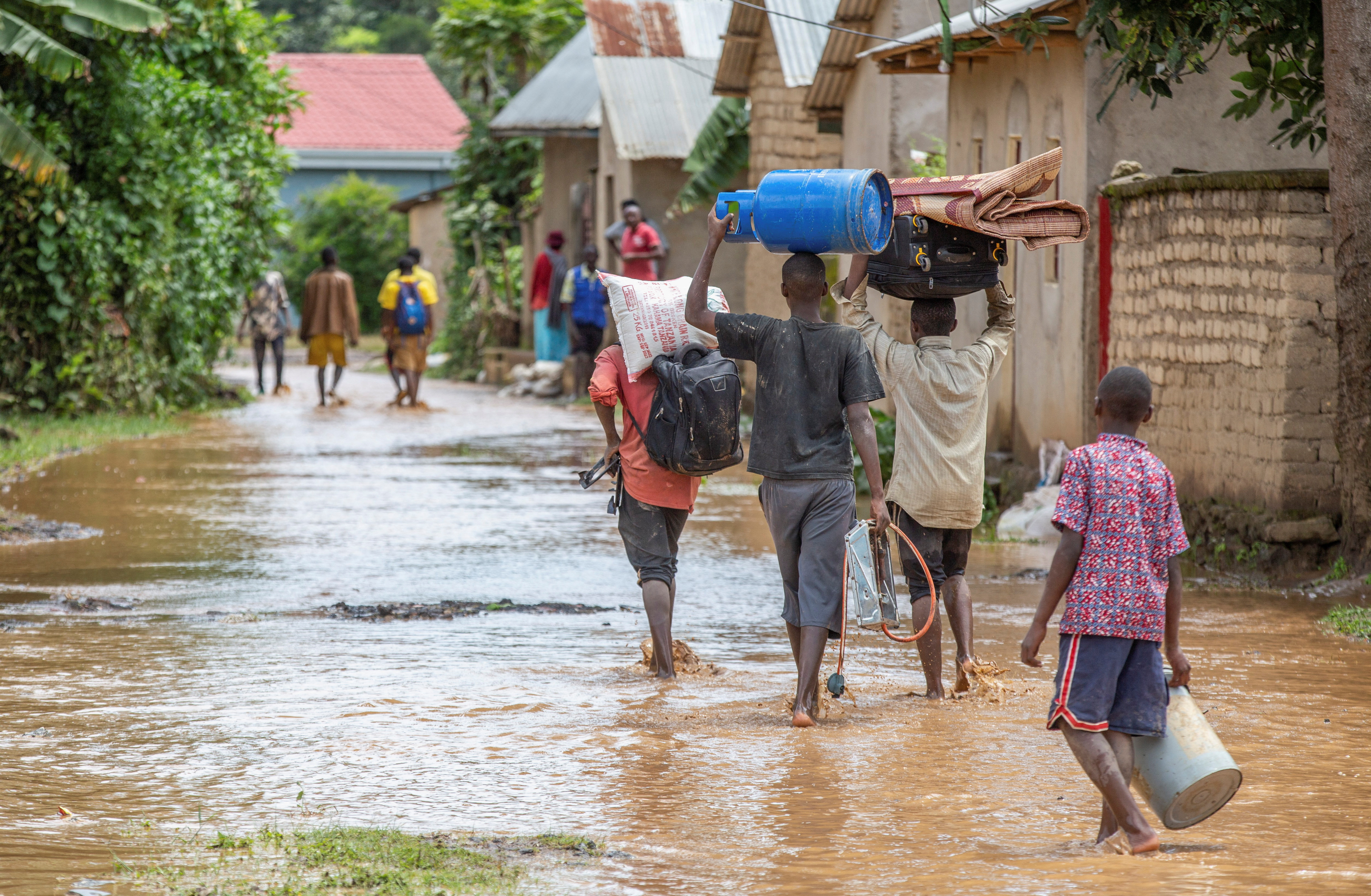 Residents wade through water after their homes were swamped following rains that triggered flooding and landslides in Rubavu district