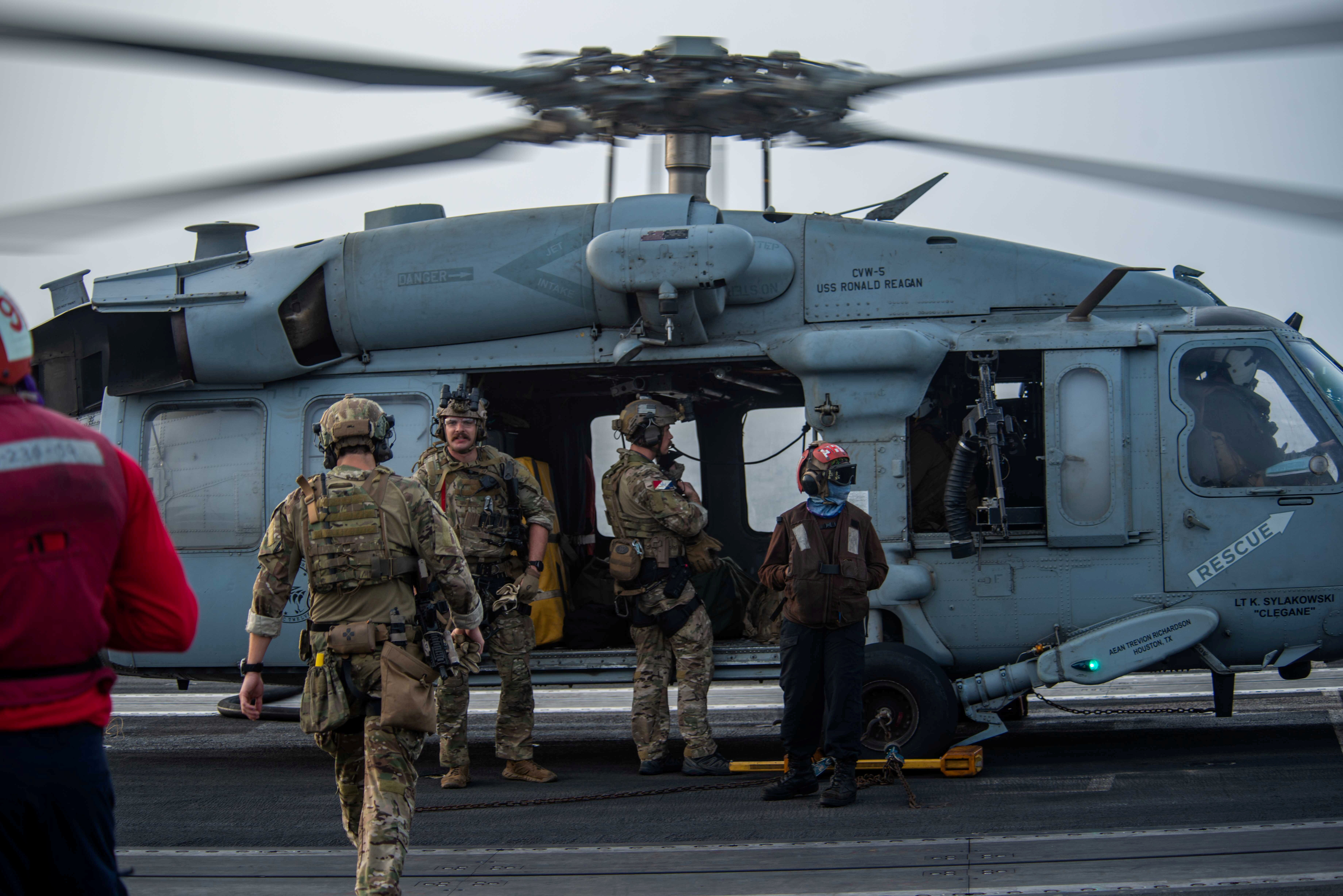 Sailors assigned to Explosive Ordnance Disposal Mobile Unit (EODMU) 5 board an MH-60S Sea Hawk helicopter, attached to the "Golden Falcons" of Helicopter Sea Combat Squadron (HSC) 12, are seen on the flight deck of aircraft carrier USS Ronald Reagan (CVN 76), in response to a call for assistance from the Mercer Street, a Japanese-owned Liberian-flagged tanker managed by Israeli-owned Zodiac Maritime, in the Arabian Sea July 30, 2021. Picture taken July 30, 2021. U.S. Navy/Handout via REUTERS 