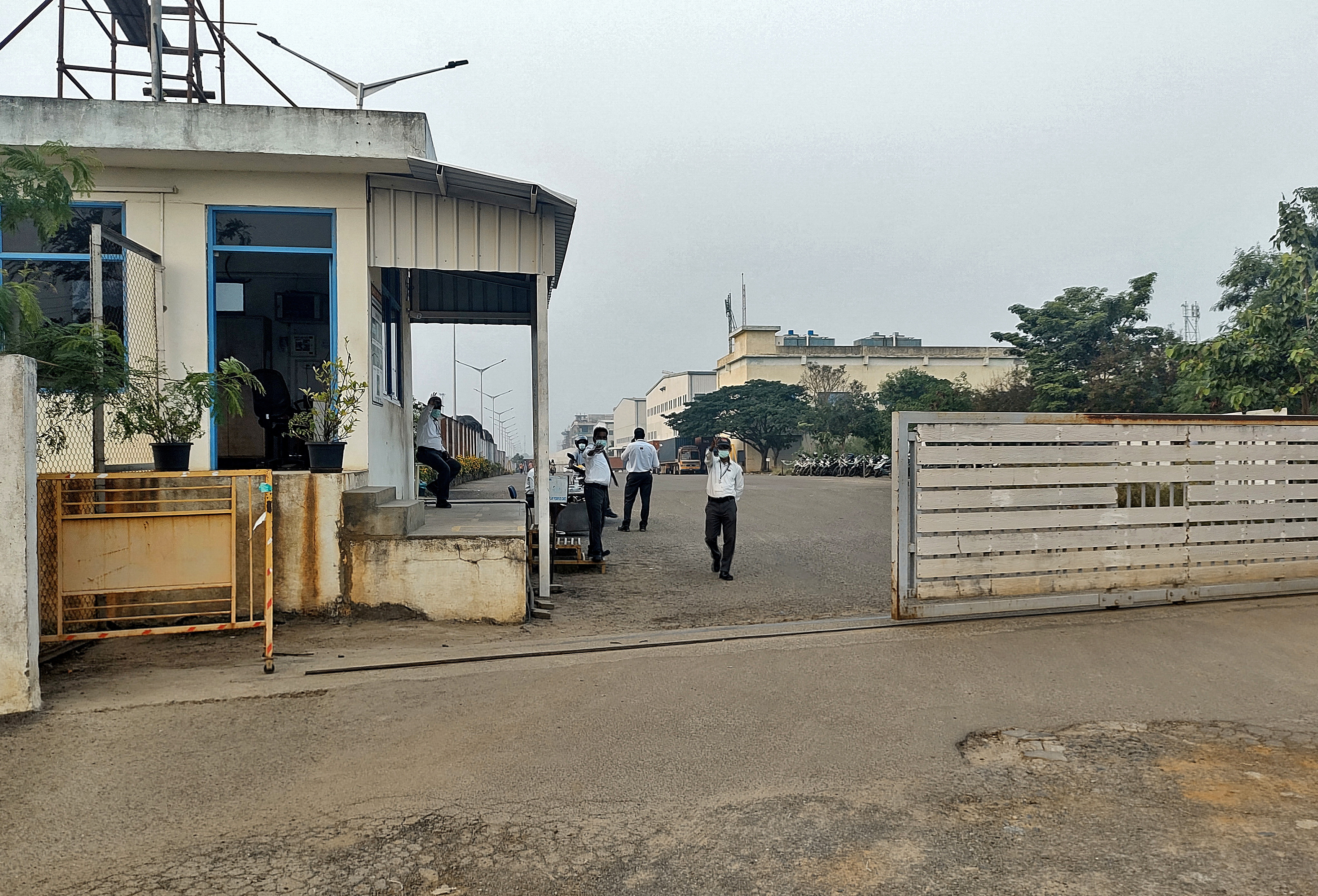 Private security guards stand at the entrance of a closed plant of Foxconn India, near Chennai