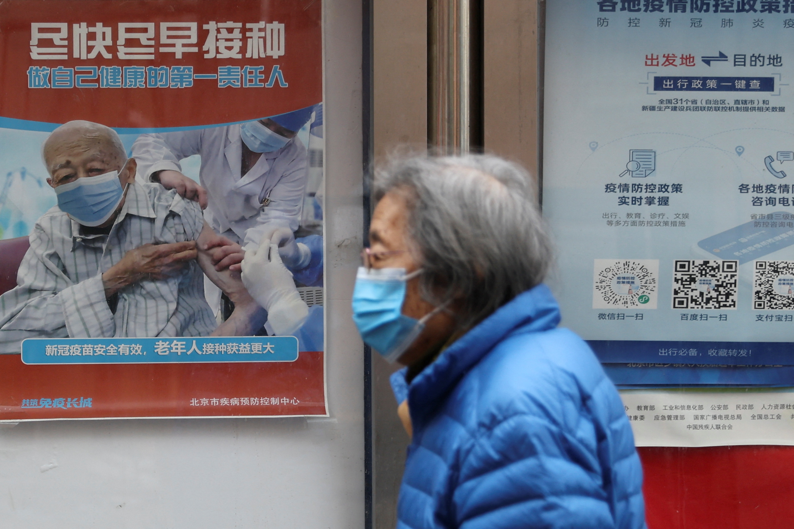 A person walks past a poster encouraging elderly people to get vaccinated against COVID-19, in Beijing