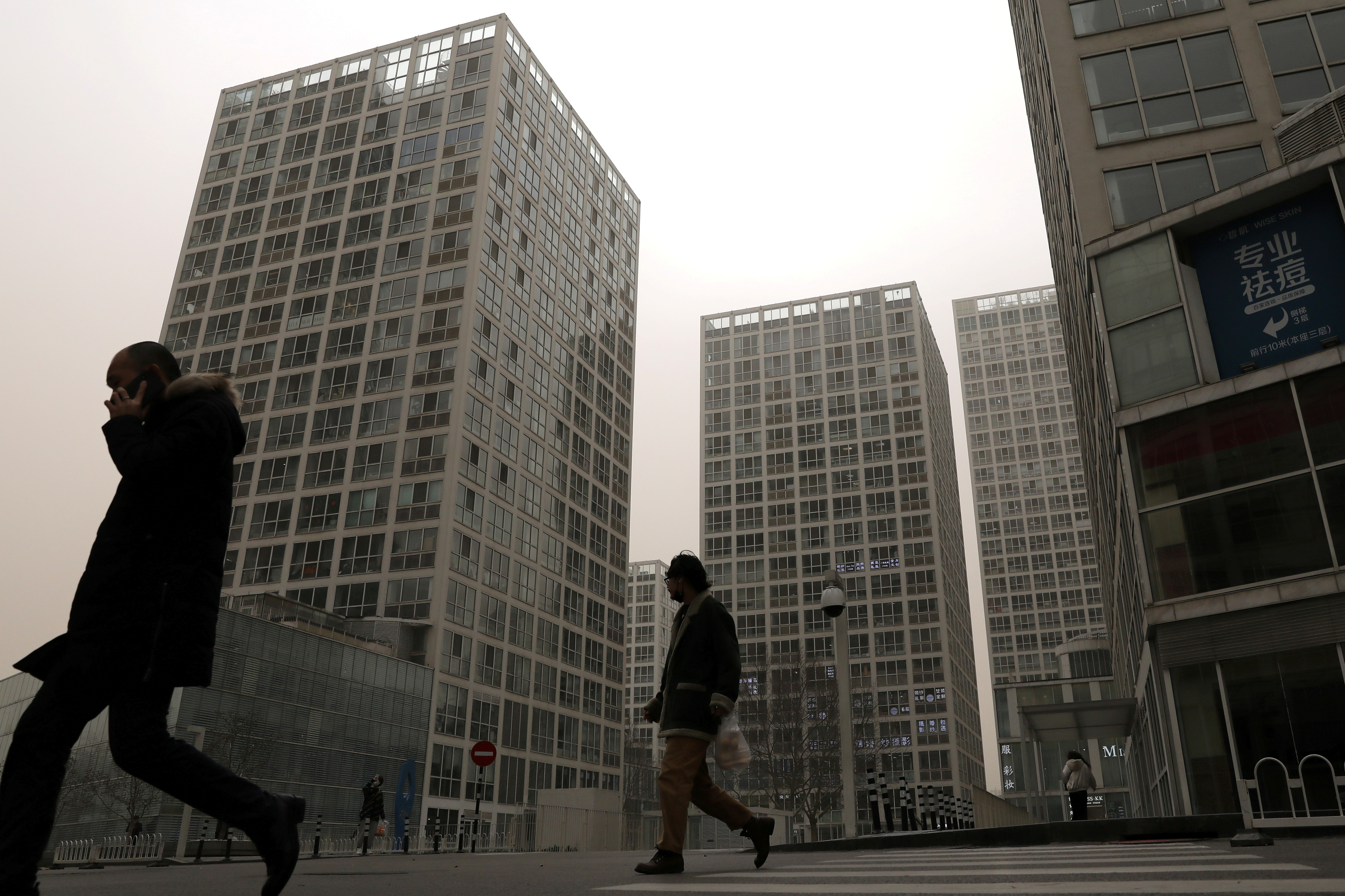 People walk past an office and commercial complex in Beijing's Central Business District (CBD)